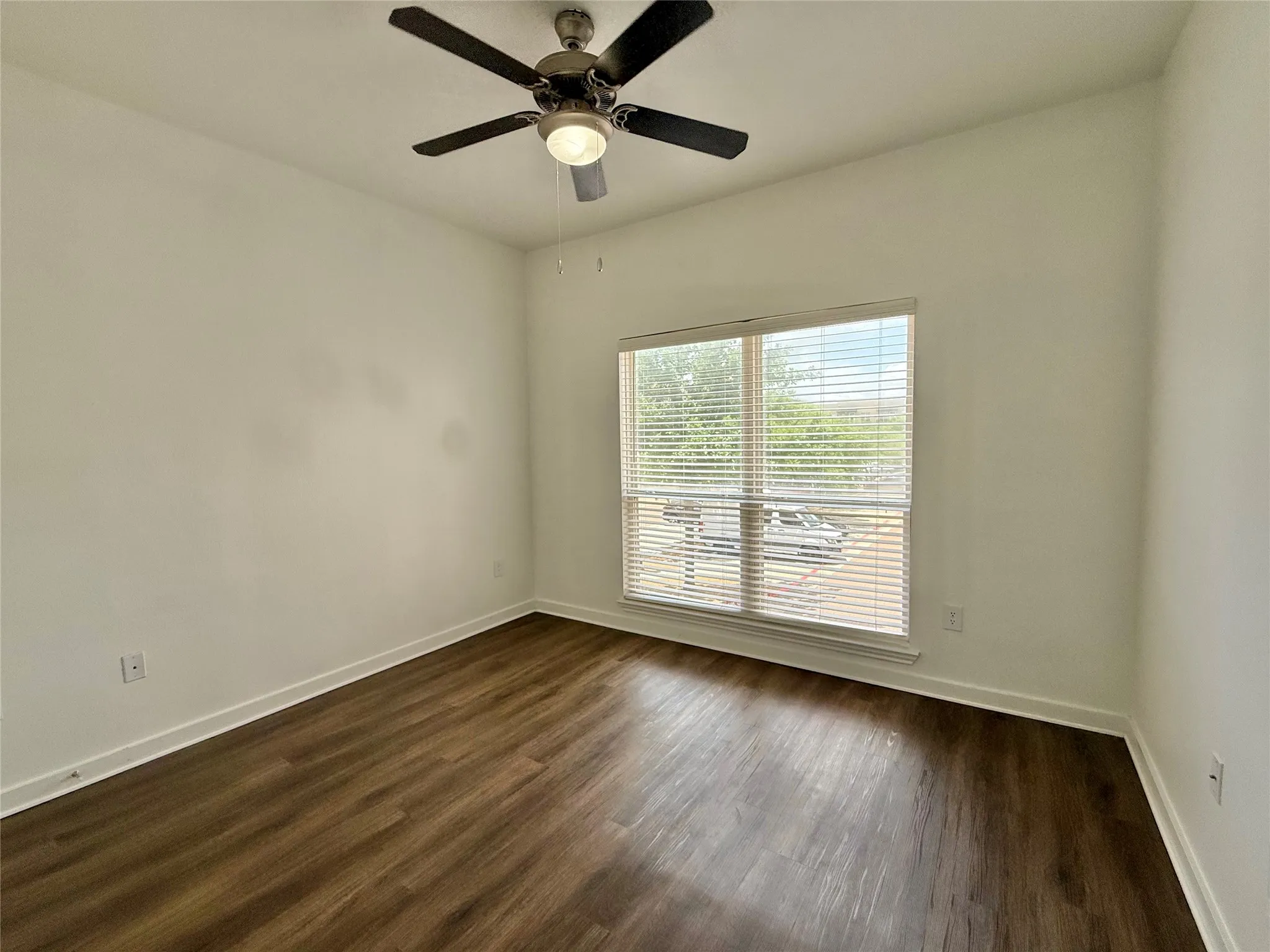 Empty room with baseboards, dark wood-style floors, and a ceiling fan