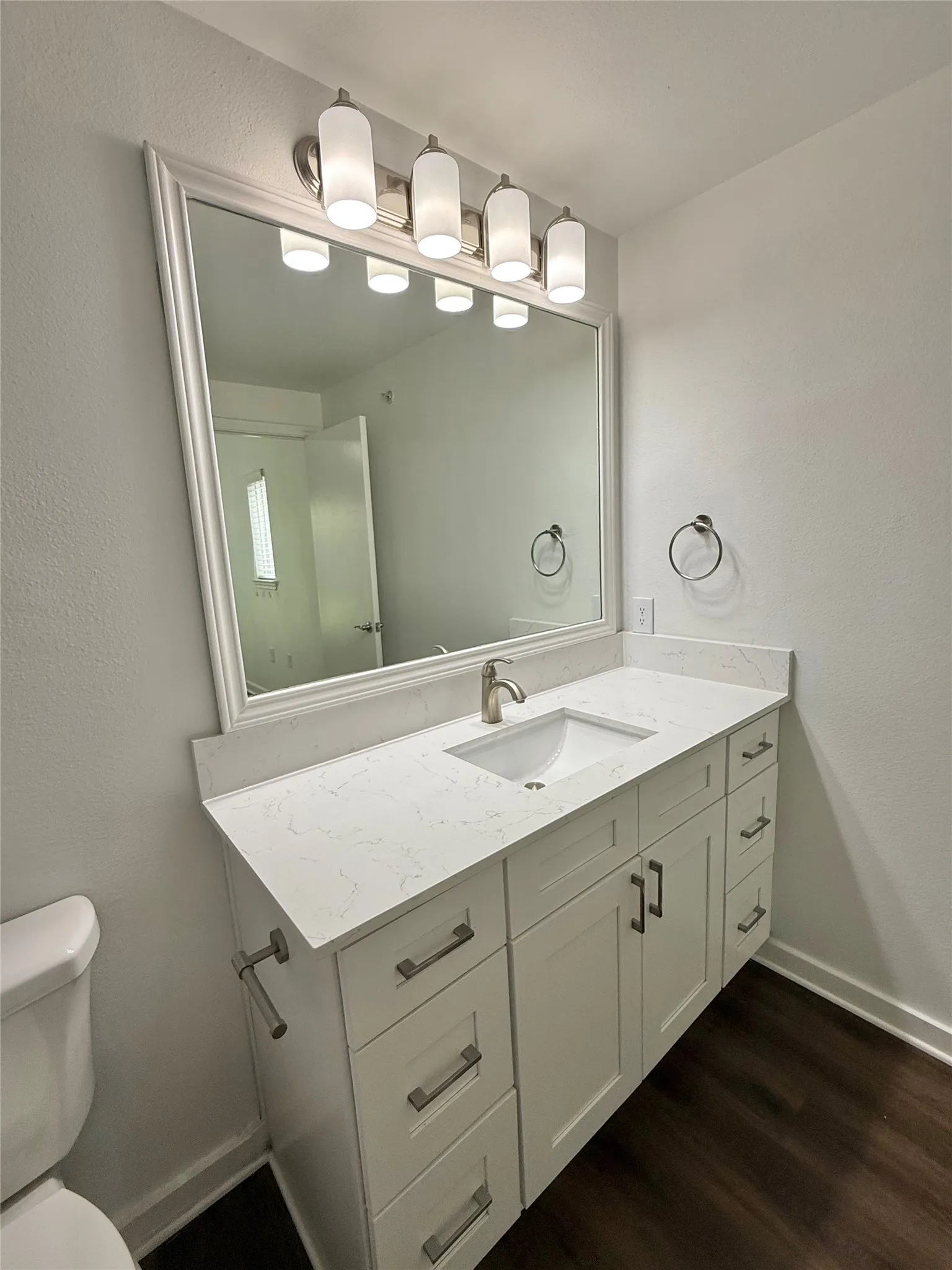 Bathroom featuring vanity, toilet, wood finished floors, and baseboards