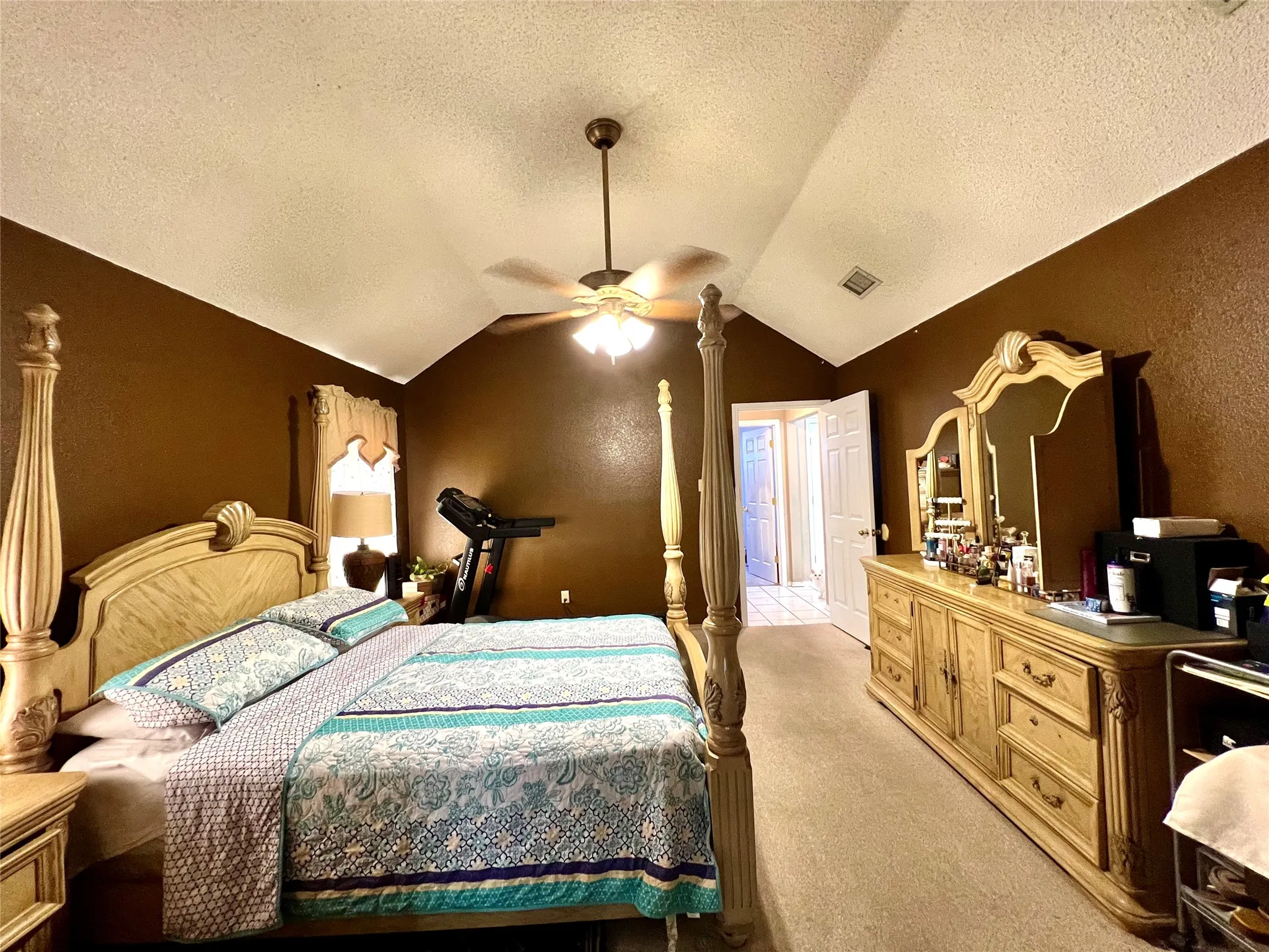 Bedroom with light colored carpet, a textured ceiling, vaulted ceiling, a textured wall, and ceiling fan