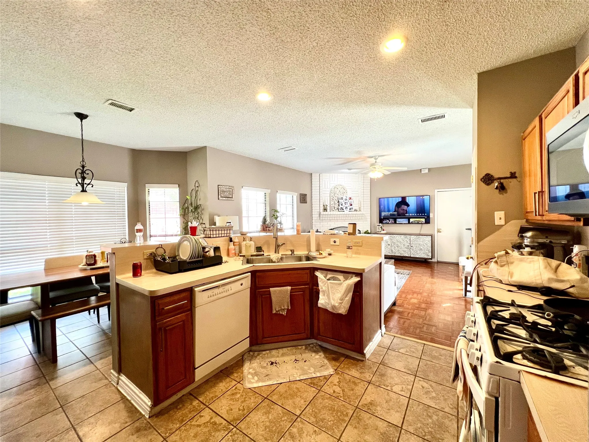 Kitchen with white appliances, a ceiling fan, light countertops, a textured ceiling, and open floor plan