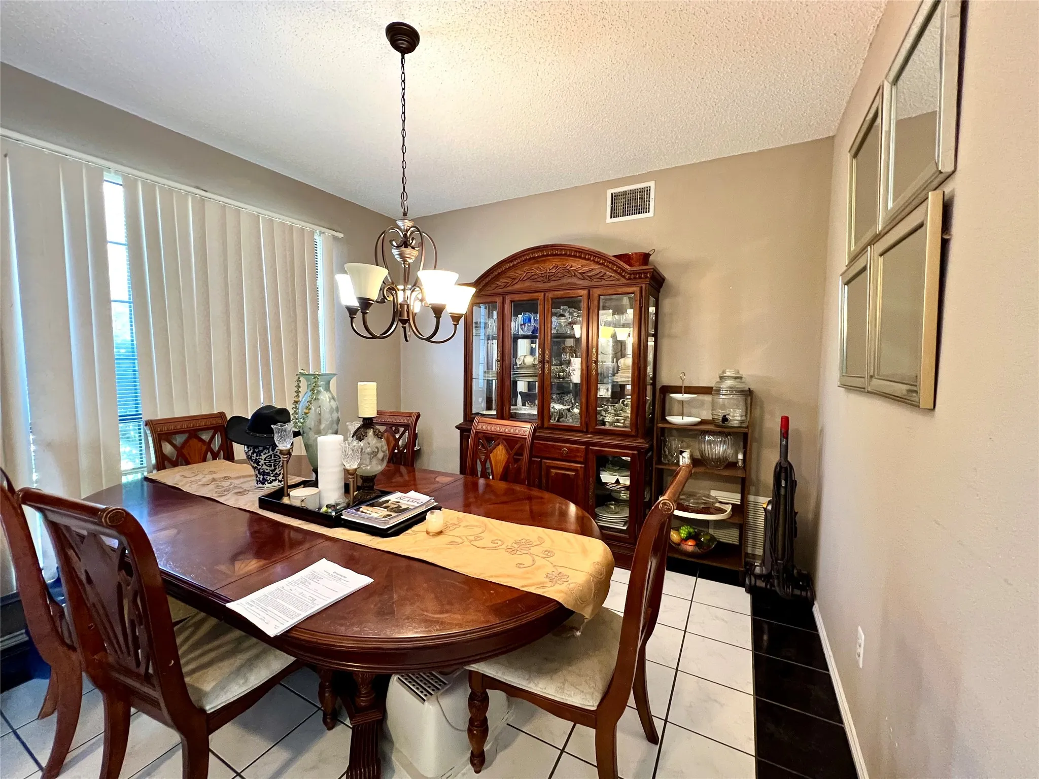 Dining room with a chandelier, light tile patterned floors, plenty of natural light, and a textured ceiling