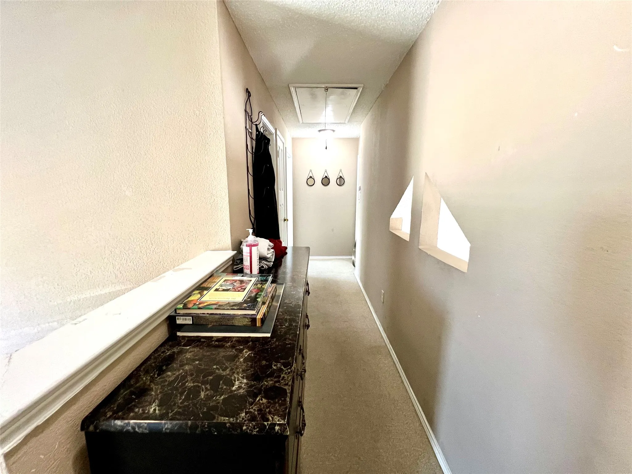 Corridor featuring attic access, carpet flooring, and a textured ceiling