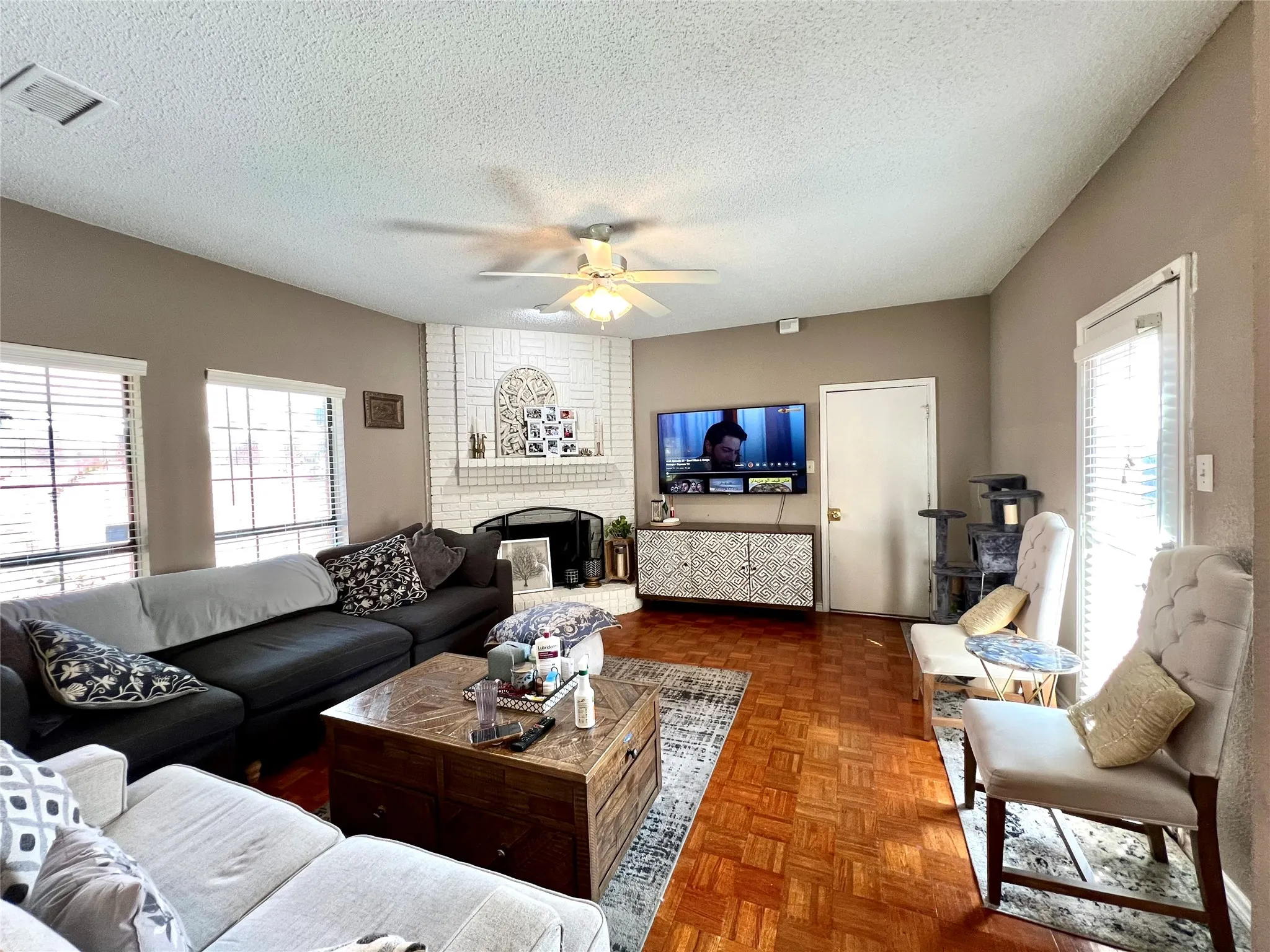 Living room with ceiling fan, healthy amount of natural light, a textured ceiling, and a fireplace
