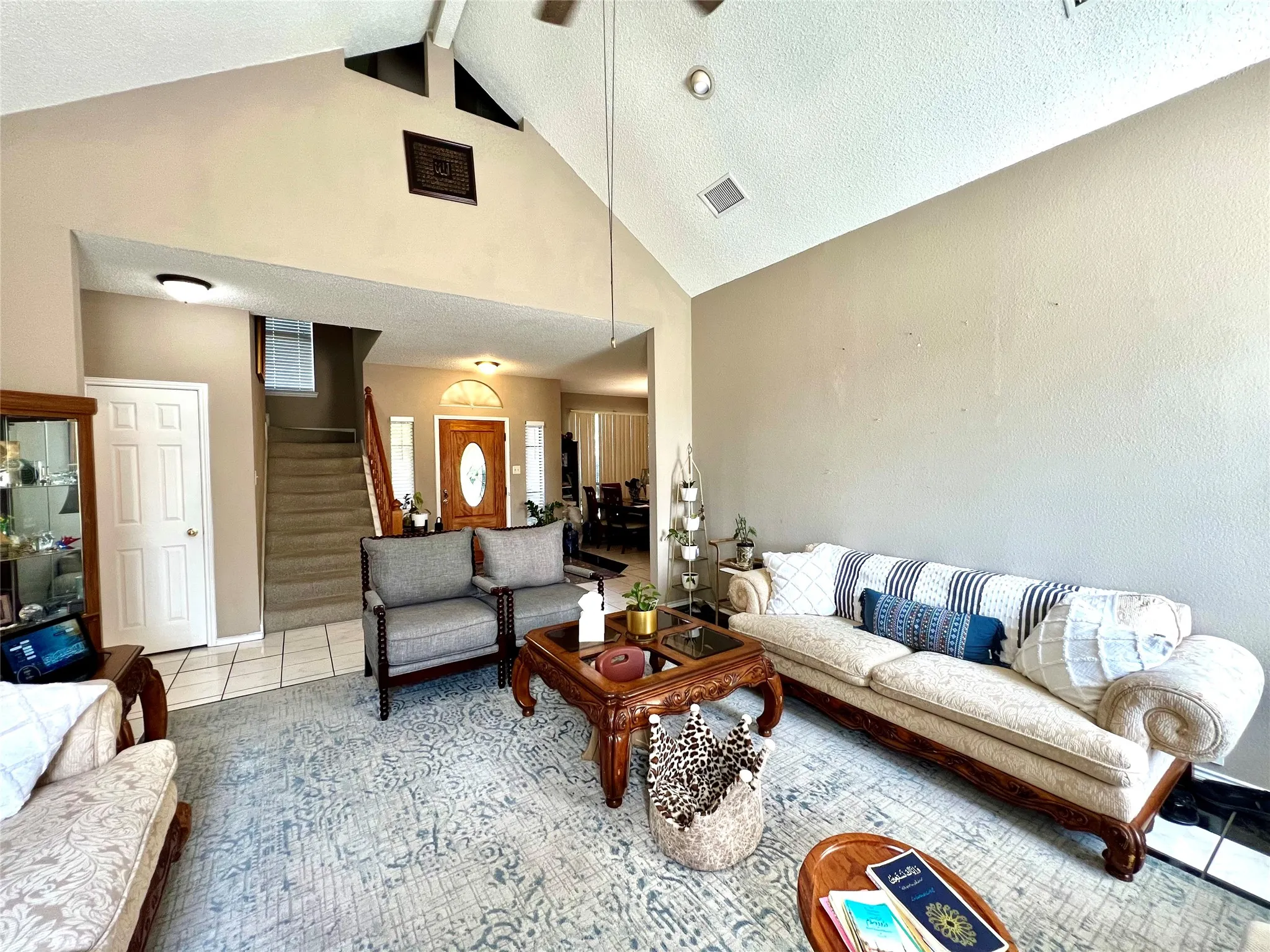 Tiled living area with stairway, high vaulted ceiling, ceiling fan, and beam ceiling