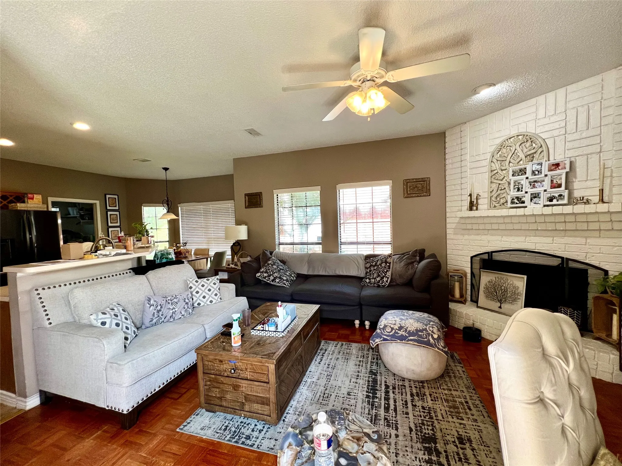 Living area with a textured ceiling, ceiling fan, a fireplace, and recessed lighting