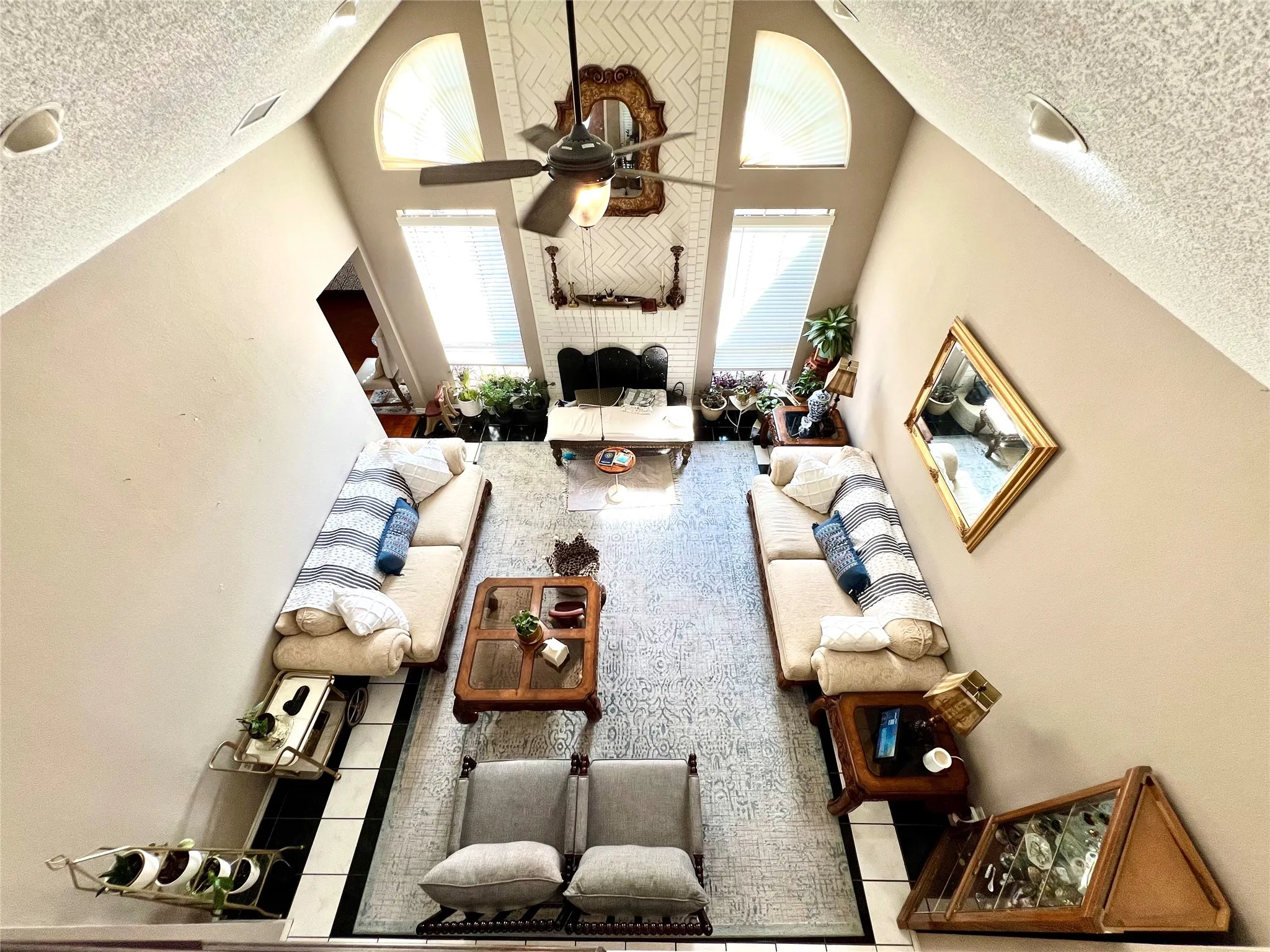 Living area with a textured ceiling, high vaulted ceiling, and ceiling fan