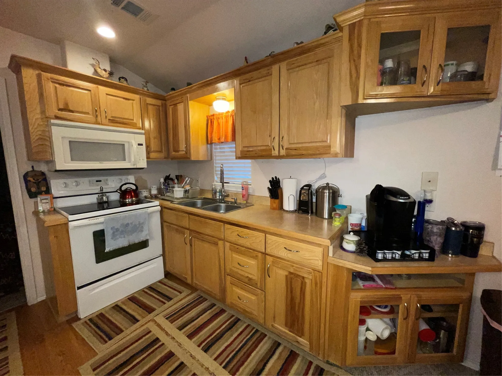 Kitchen with stove, sink, wood-type flooring, and lofted ceiling