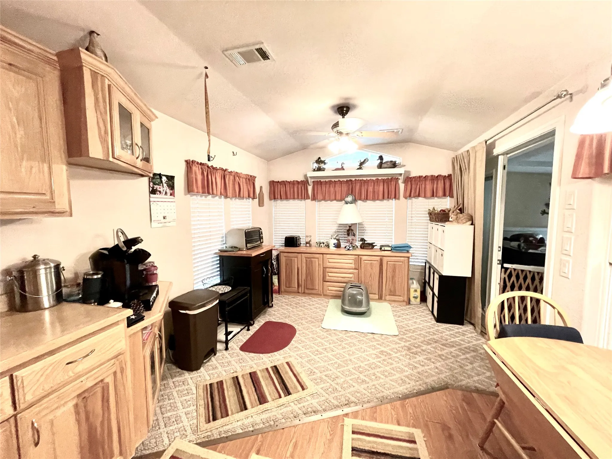 Kitchen featuring ceiling fan, light wood-type flooring, and vaulted ceiling