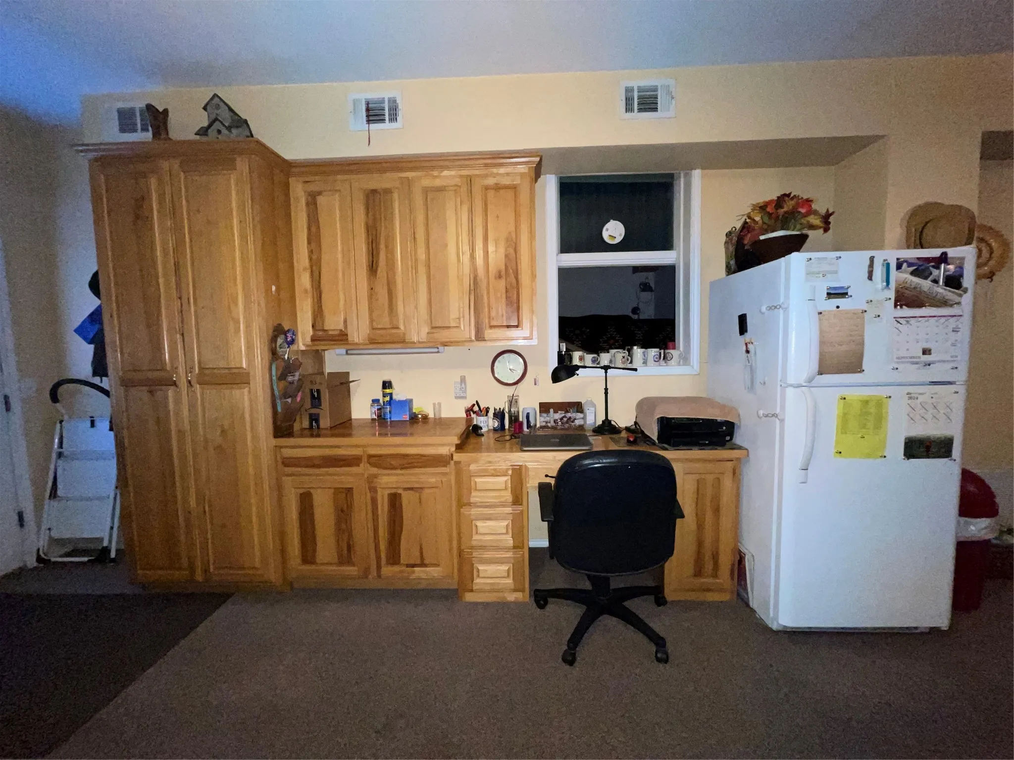 Kitchen with built in desk, refrigerator, and dark colored carpet