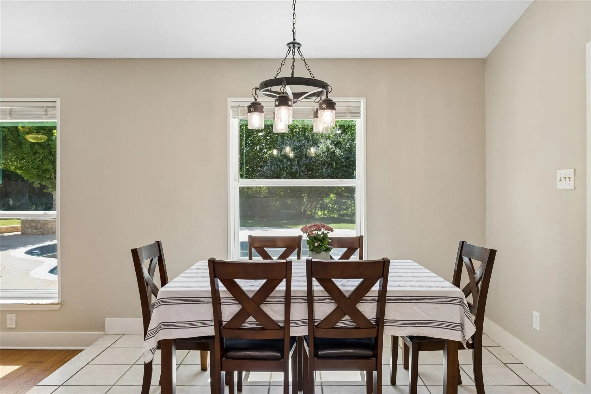 Dining area featuring a contemporary five-light chandelier, a large central window, and an additional side window