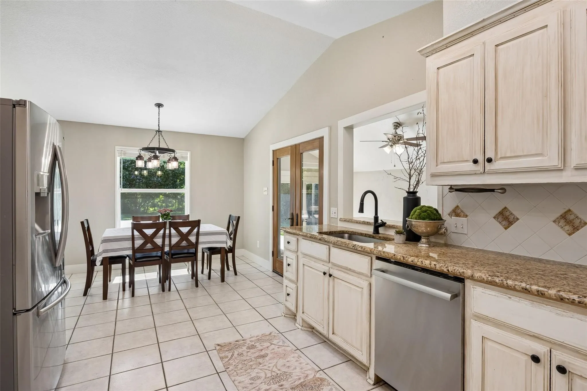 Kitchen featuring white cabinetry, granite-finish countertops, and a tile backsplash with decorative accents