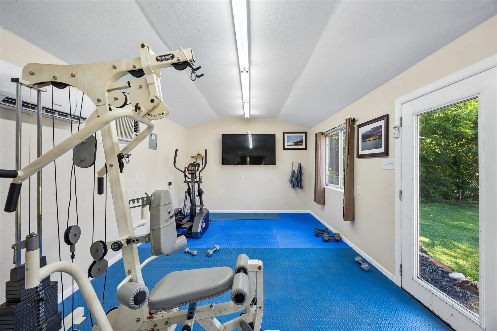 Dedicated recreational space with blue cushioned flooring, a full-lite exterior door, and two windows providing natural light