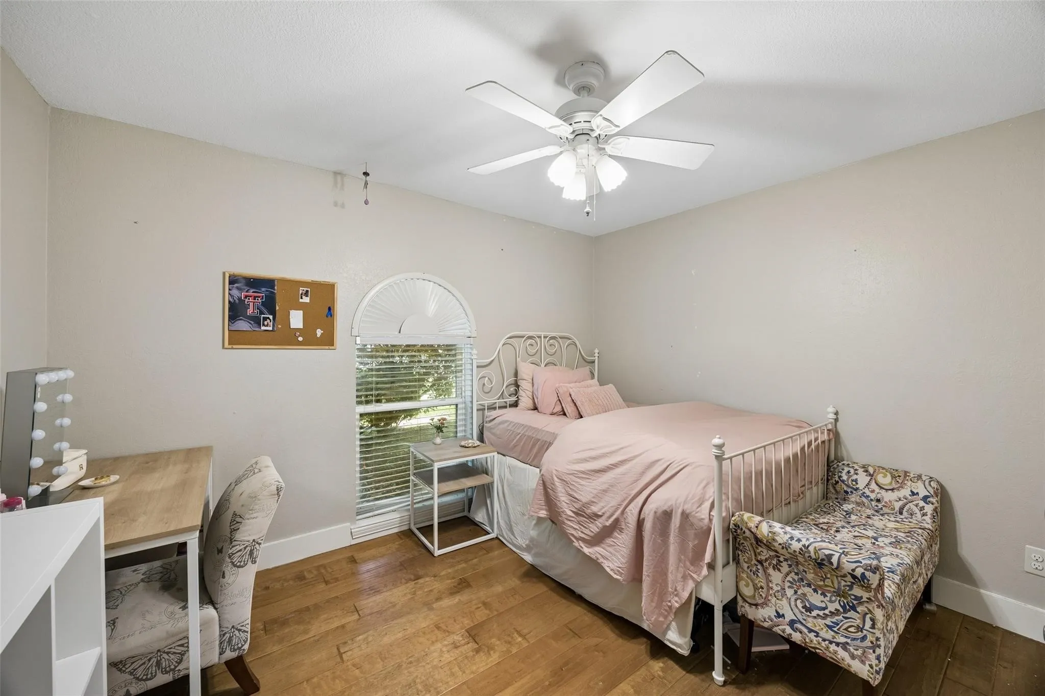 Room featuring wood-finish flooring, a ceiling fan, and white baseboards