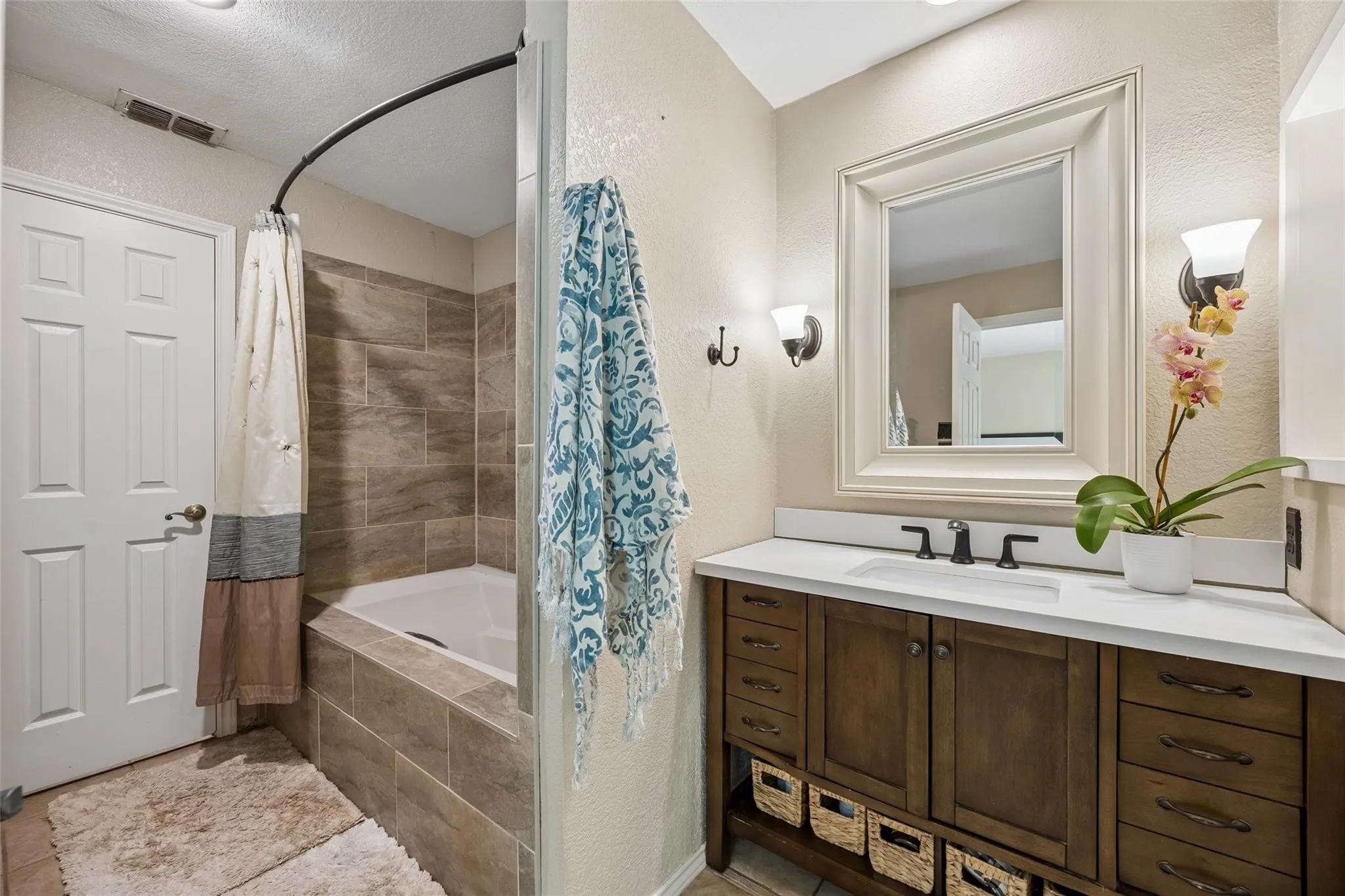 Bathroom featuring a dark wood vanity with a white countertop and undermount sink, framed mirror, and two wall-mounted sconces
