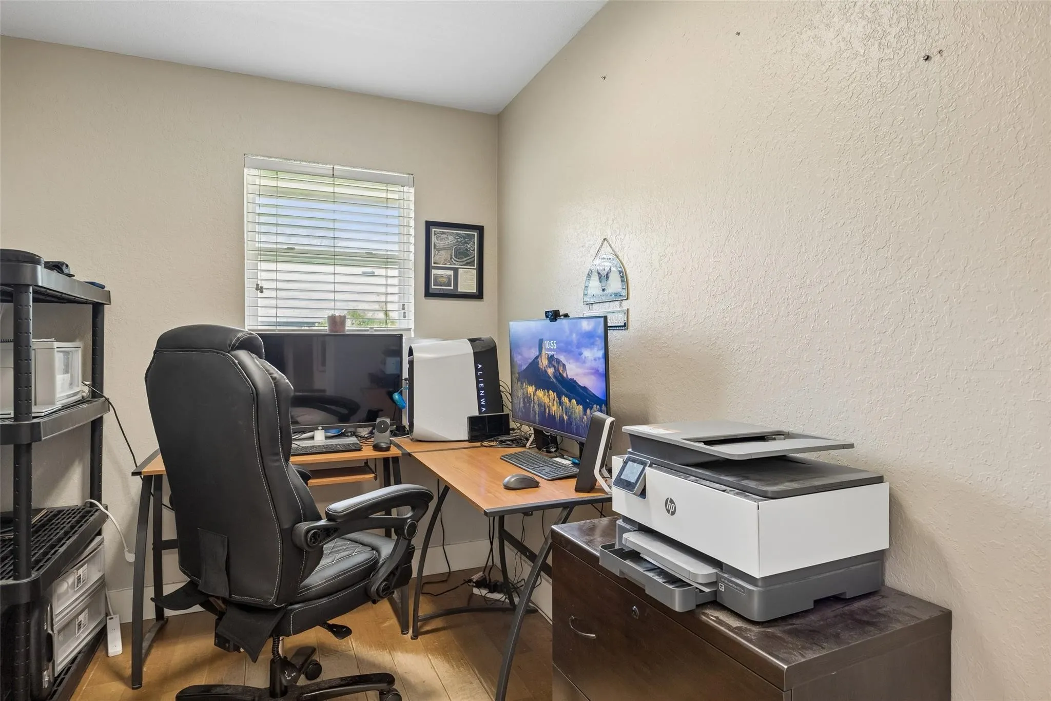 Interior room featuring light-toned textured walls, wood-finish flooring, and a window with horizontal blinds
