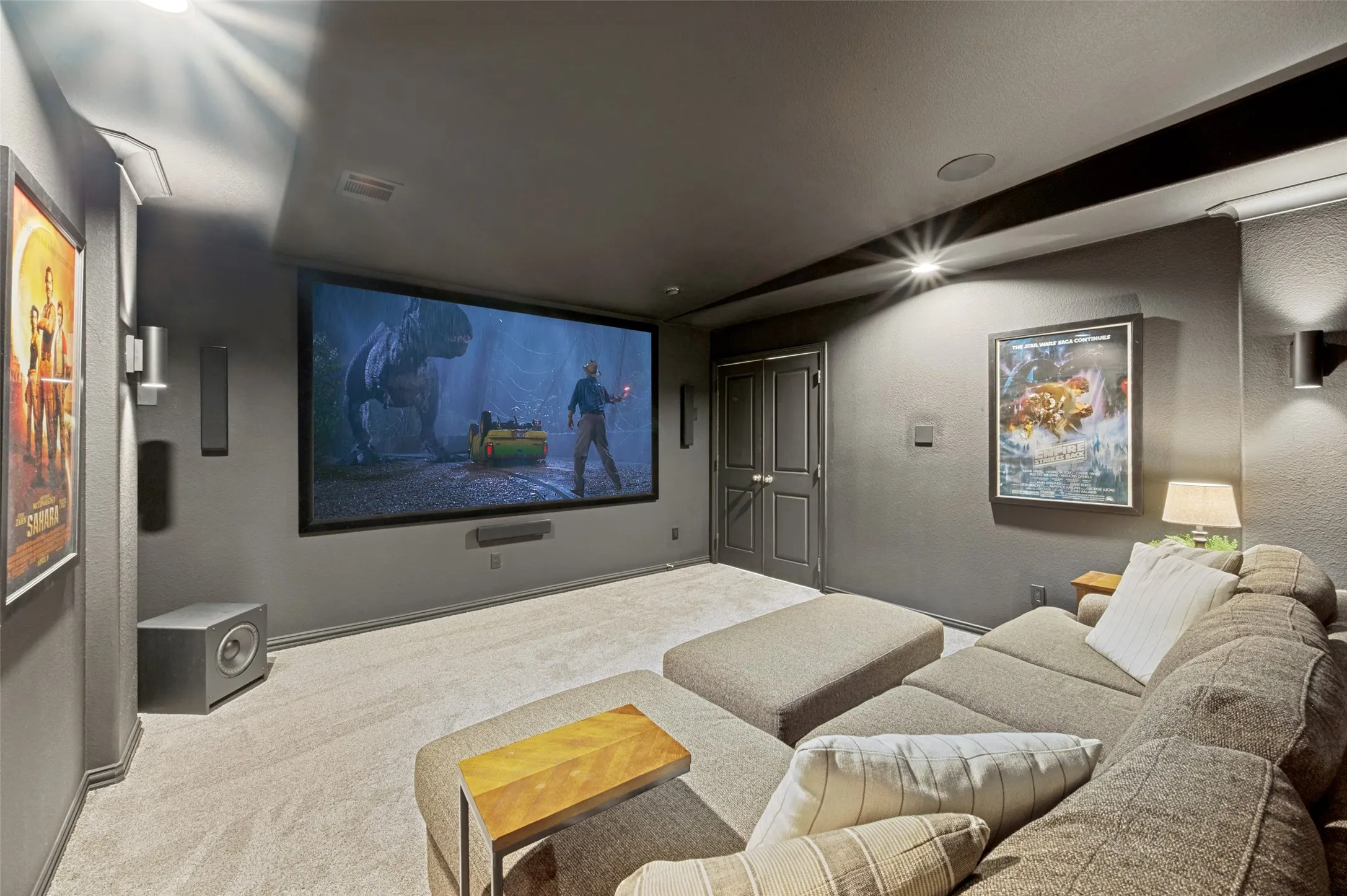 The ultimate at-home theater experience, this spacious media room features a large movie screen, high-end projector, decorative wall sconces, and plush low-profile carpet for added comfort and style. Designed for immersive movie nights, sporting events, and entertaining, this private retreat brings the cinematic experience right to your home.