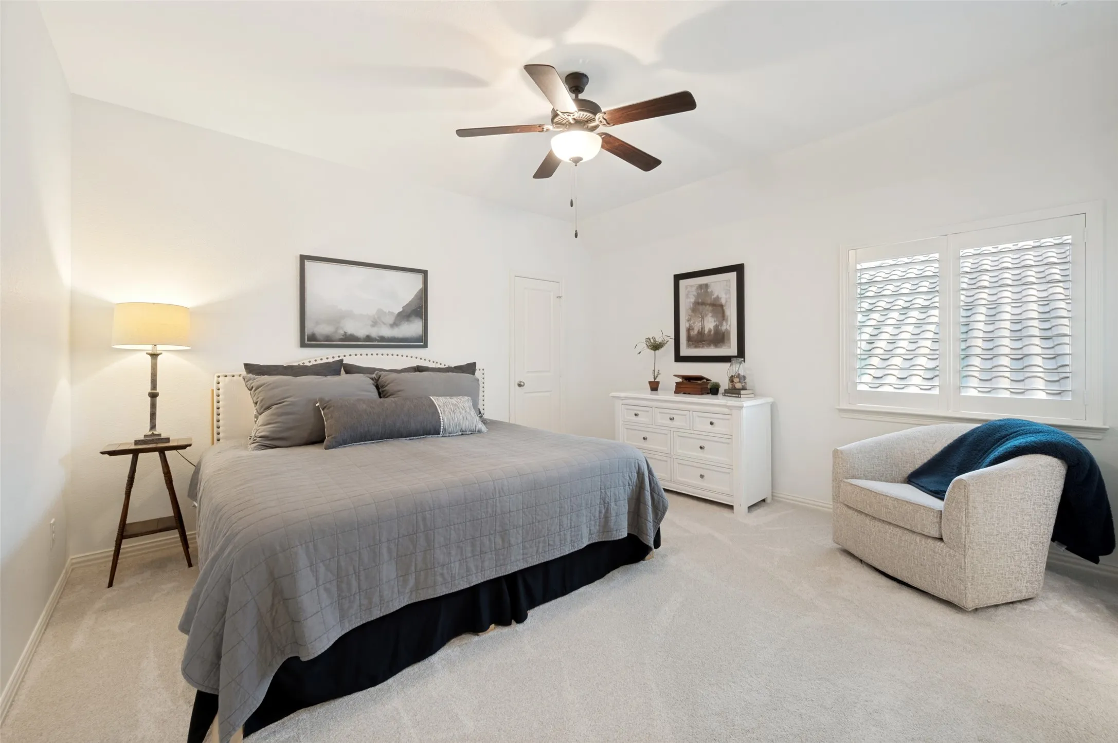 A spacious secondary bedroom offers a comfortable private retreat with super-plush low-profile carpet, plantation shutters, a generous walk-in closet, and its own ensuite bath. The oversized layout provides plenty of room for a sitting area, while abundant natural light creates a bright and inviting atmosphere.
