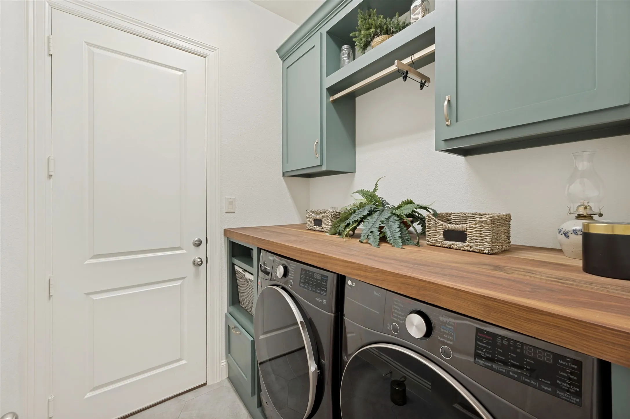 A beautifully designed laundry room combines style and functionality with custom built-in cabinetry, rich walnut countertops, and a dedicated linen closet. Abundant storage and generous counter space make laundry and organization effortless while elevated finishes give this hardworking space a polished, custom feel.