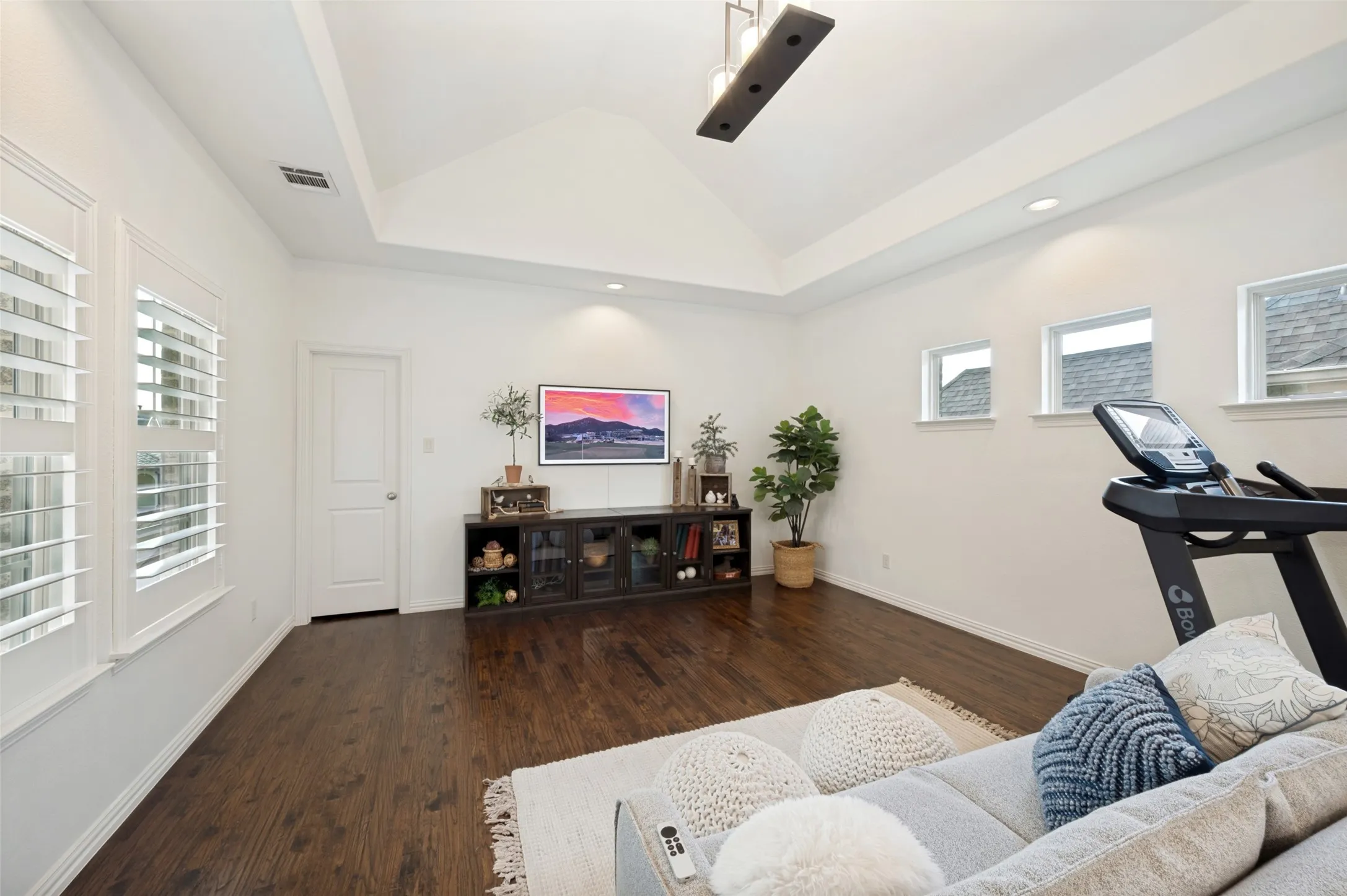 This versatile upstairs game room offers plenty of space for lounging, gaming, fitness, or a secondary living area. Hardwood floors, abundant natural light, and a vaulted ceiling with a modern chandelier create a bright, open feel. A door provides direct access to the terrace, extending the living space outdoors, while a large storage closet and finished-out walk-in attic space provide exceptional storage and functionality.