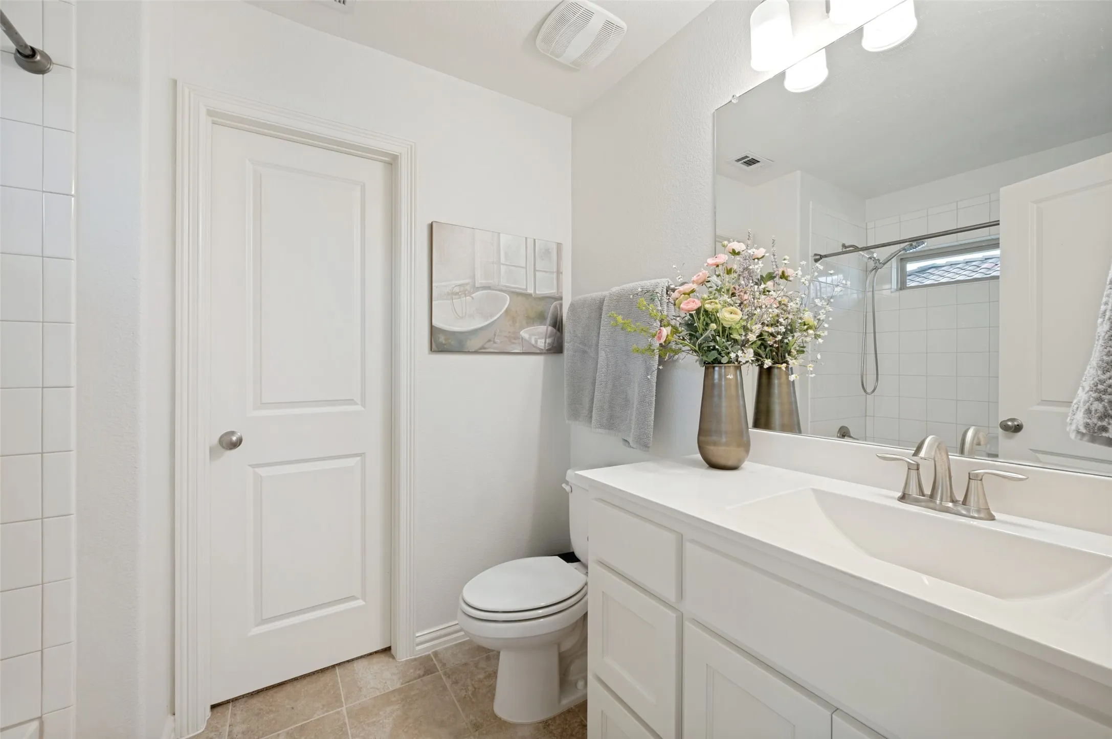 A bright and inviting ensuite bath offers comfort and convenience with a shower/tub combination, spacious vanity, generous counter space, and ample cabinetry. Neutral finishes and a large mirror create a fresh, clean feel, making this private bath a perfect complement to the secondary bedroom.