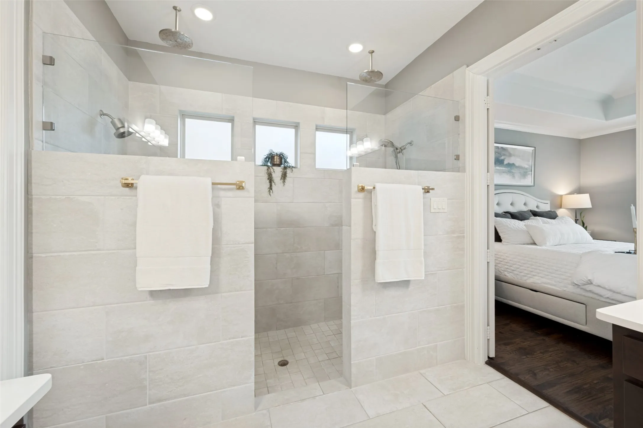 A luxurious oversized walk-in shower creates a spa-like retreat in the primary ensuite, complete with dual shower heads and dual rainfall shower heads for the ultimate experience. Floor-to-ceiling tile, frameless glass, and a spacious open design add a clean, sophisticated feel to this beautifully appointed bath.
