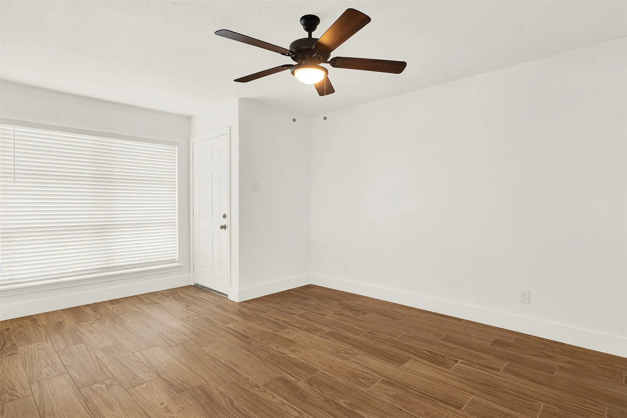 Empty room with wood finished floors and a ceiling fan