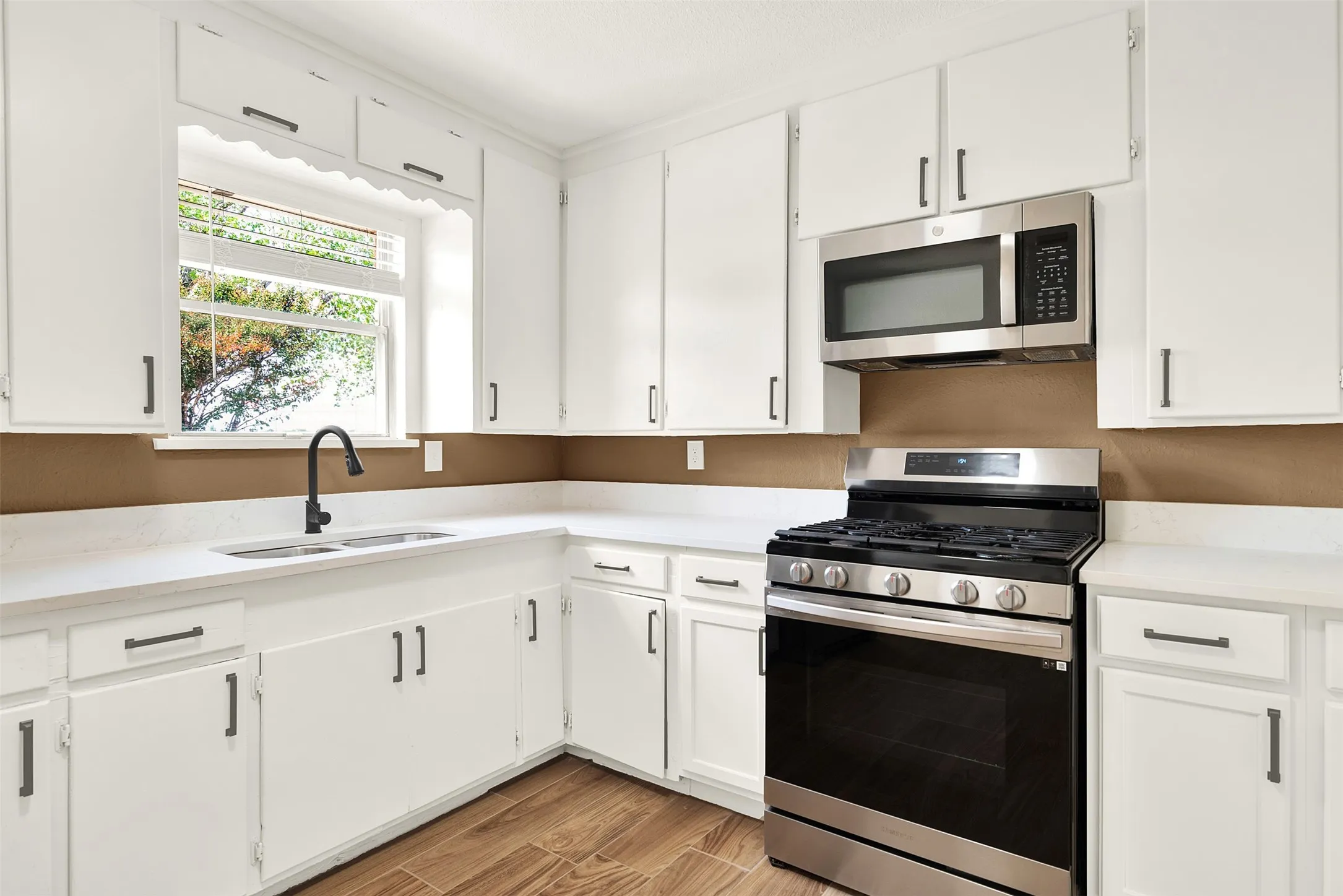 Kitchen with appliances with stainless steel finishes, light countertops, white cabinets, and light wood-style floors