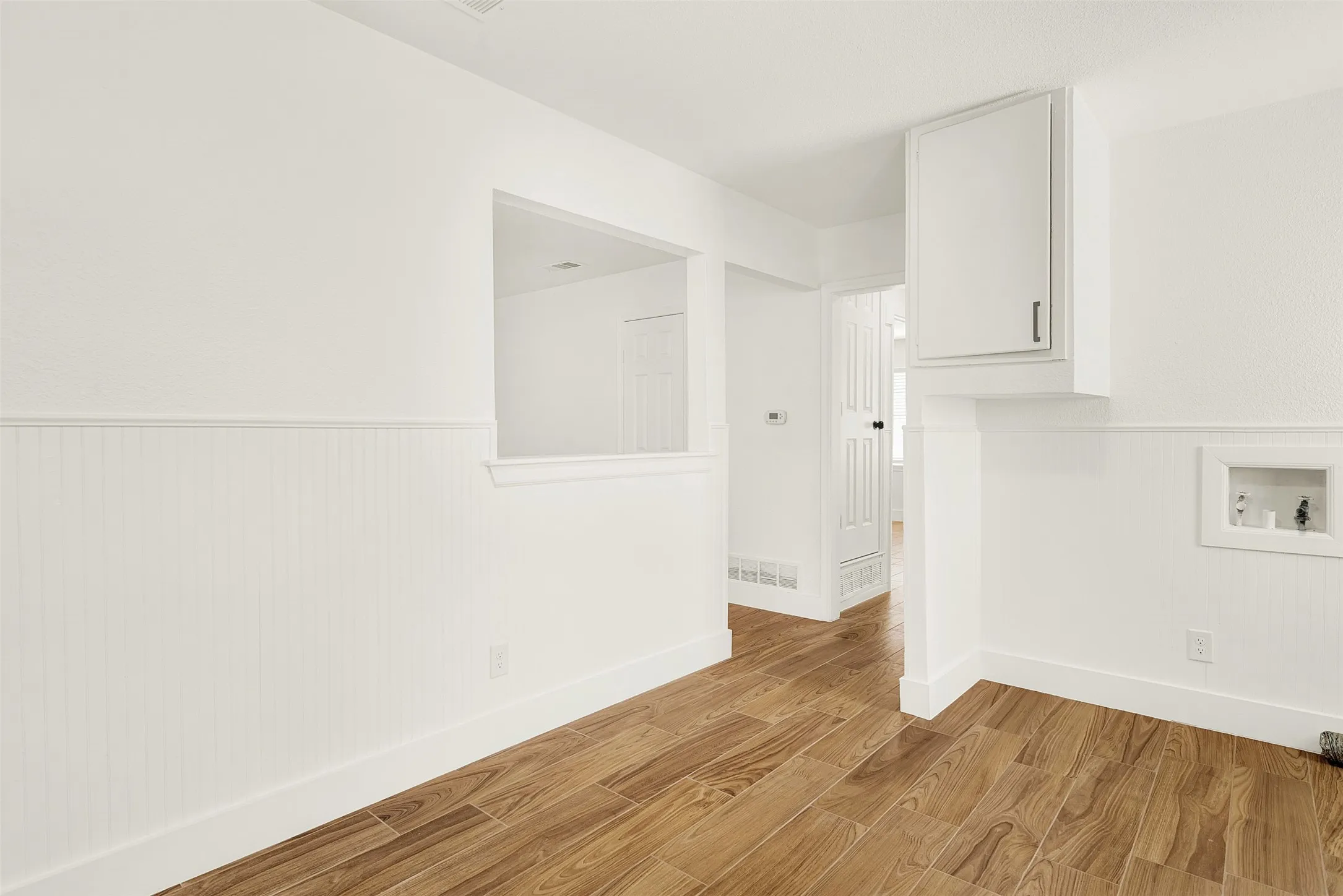 Washroom with light wood-style floors, wainscoting, and hookup for a washing machine