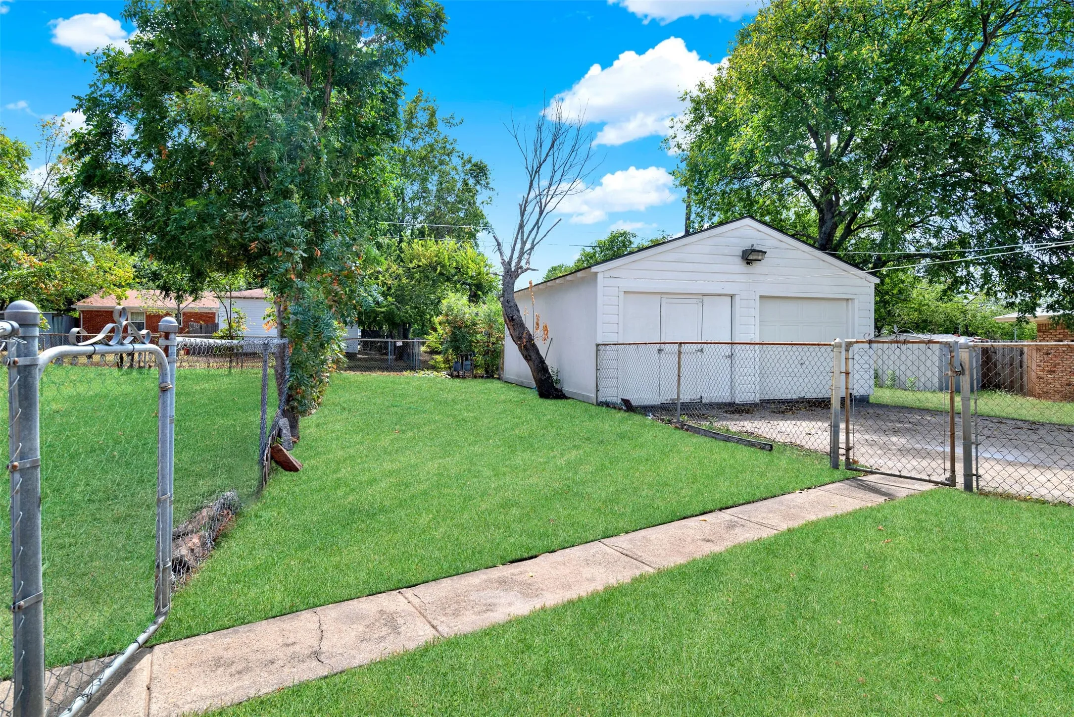 View of yard featuring a detached garage, a gate, and an outdoor structure