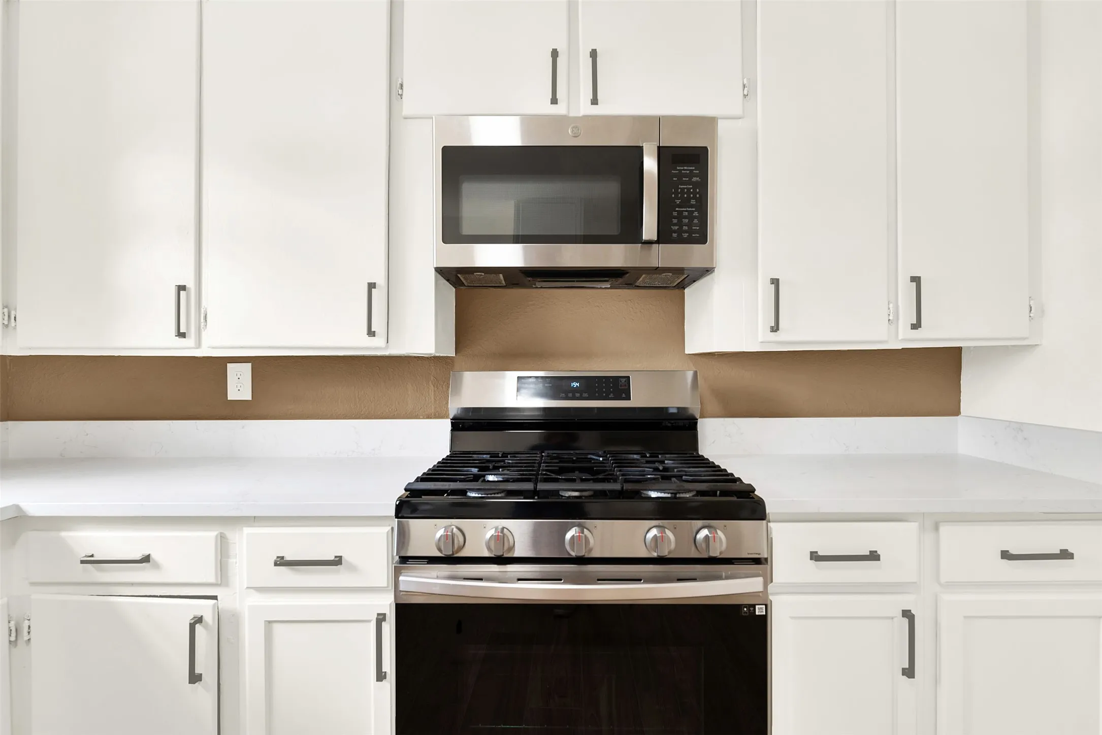 Kitchen with appliances with stainless steel finishes, light countertops, and white cabinets