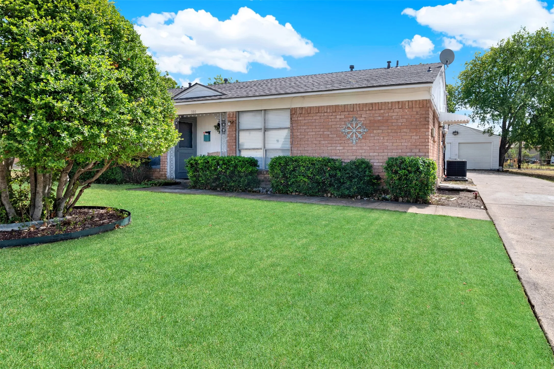 Ranch-style home with brick siding, a front yard, a garage, driveway, and roof with shingles