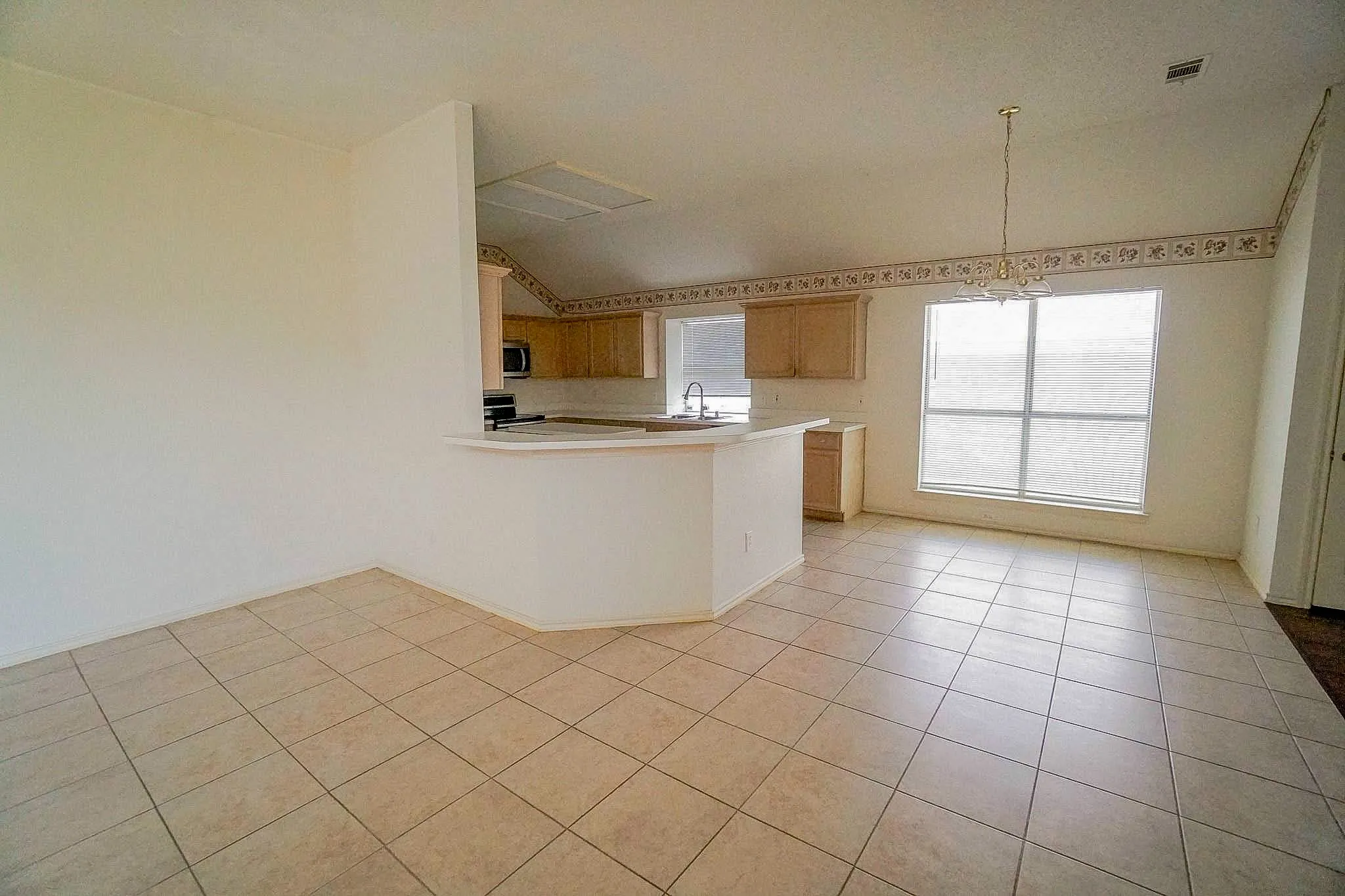 Ceramic tile flooring, kitchen with wood cabinetry, stainless steel microwave, and a breakfast bar