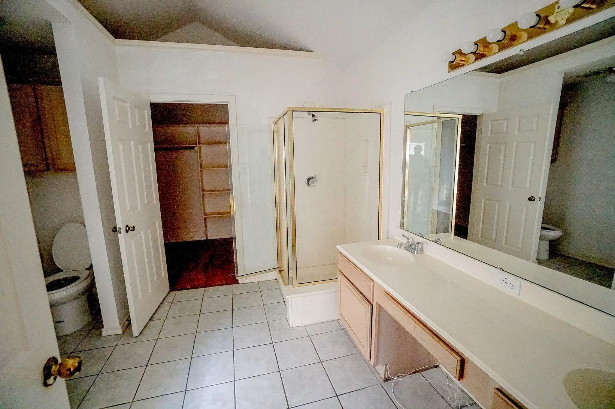 Spacious bathroom featuring a dual vanity, large wall mirror, enclosed shower, and tile flooring