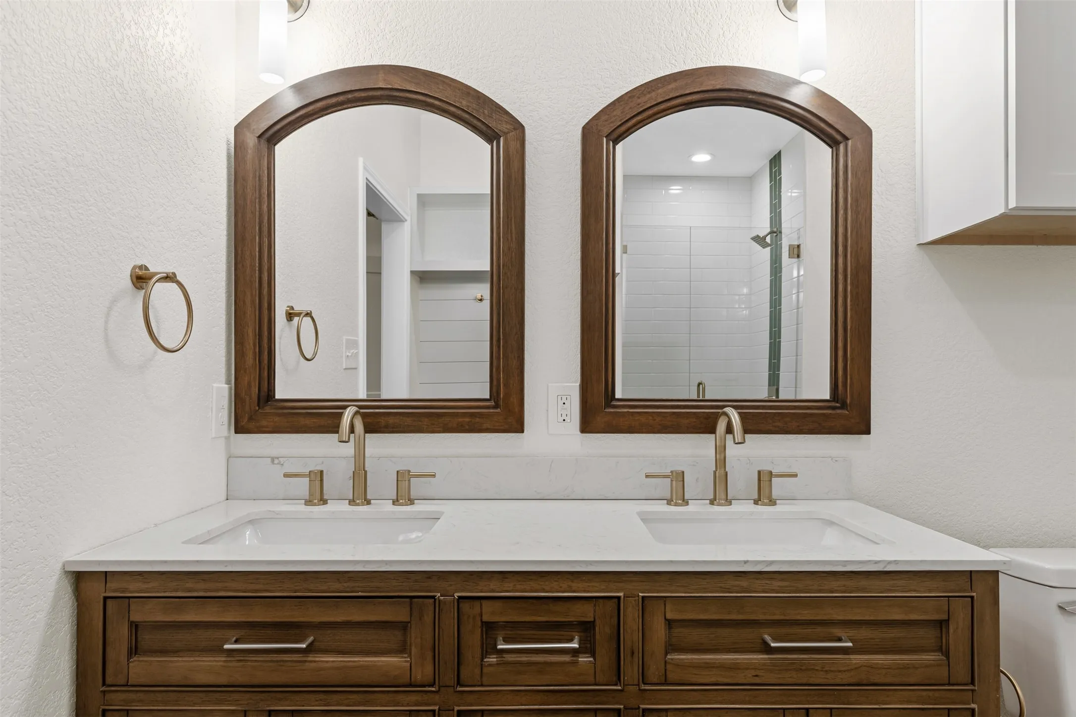 Bathroom featuring double vanity, toilet, and a shower