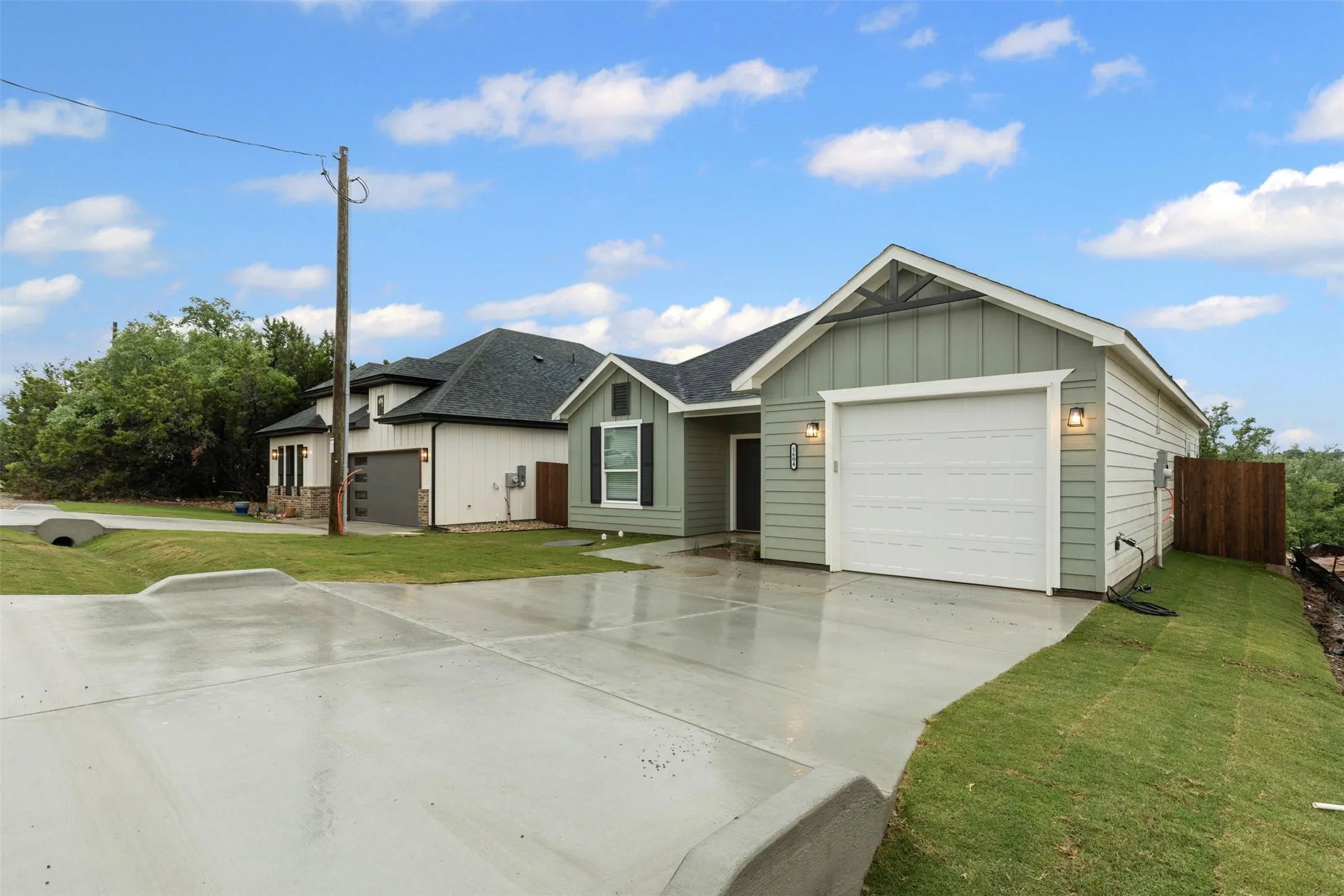 Single story home featuring board and batten siding, a shingled roof, concrete driveway, and a garage