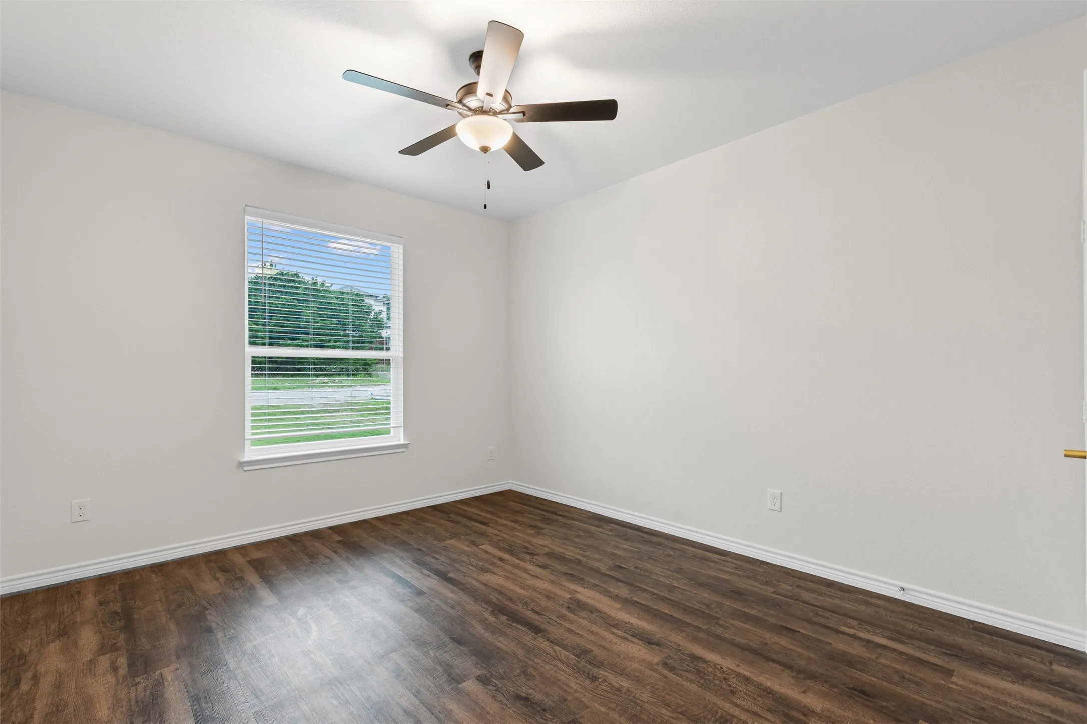 Empty room featuring dark wood finished floors, baseboards, and ceiling fan