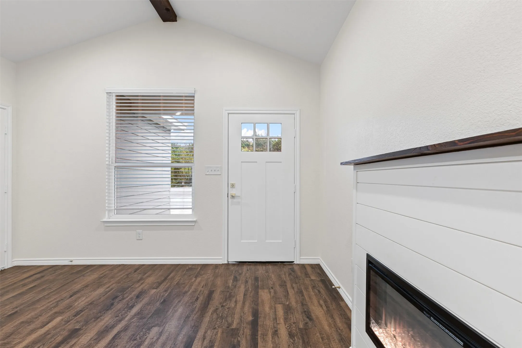 Entrance foyer featuring dark wood-style floors, baseboards, and a glass covered fireplace