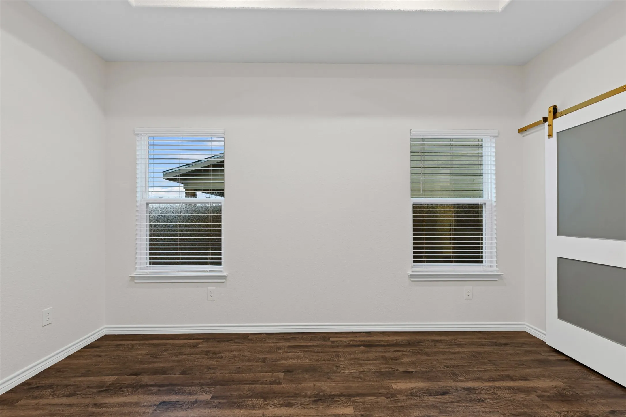 Spare room featuring wood finished floors, baseboards, and a barn door