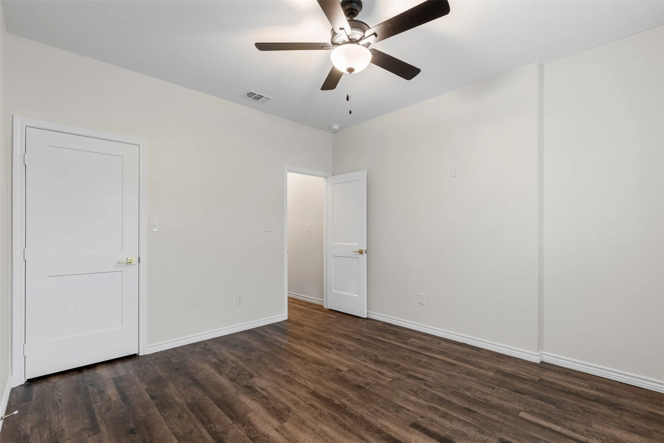 Unfurnished bedroom featuring dark wood finished floors, baseboards, and a ceiling fan