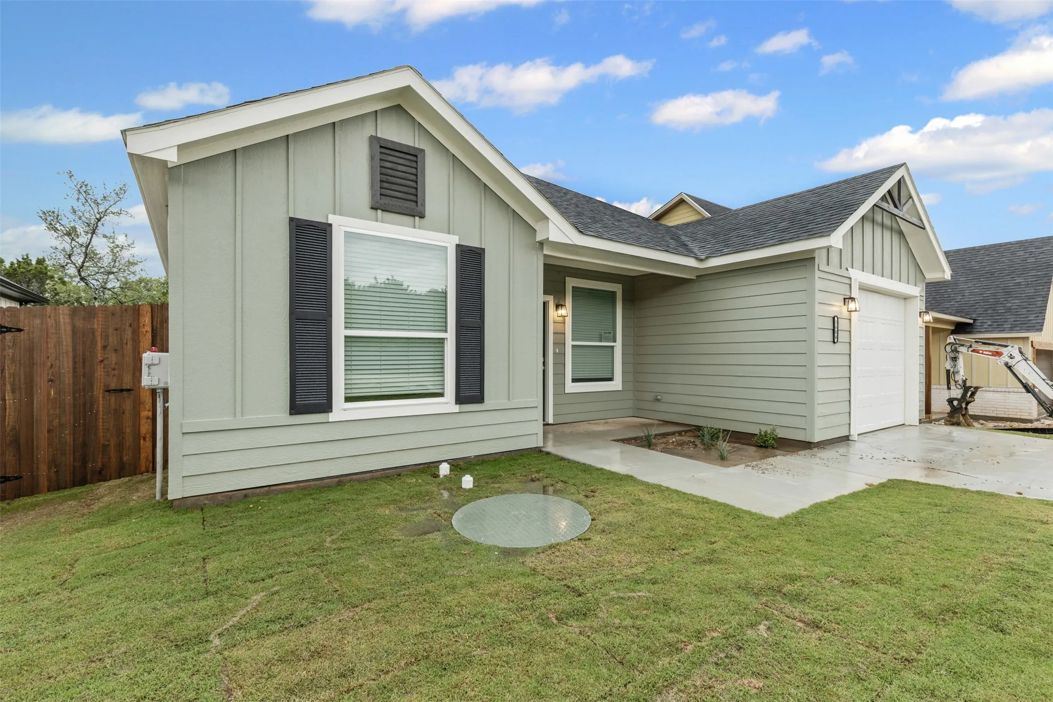 View of front of house with board and batten siding, a garage, concrete driveway, and a shingled roof
