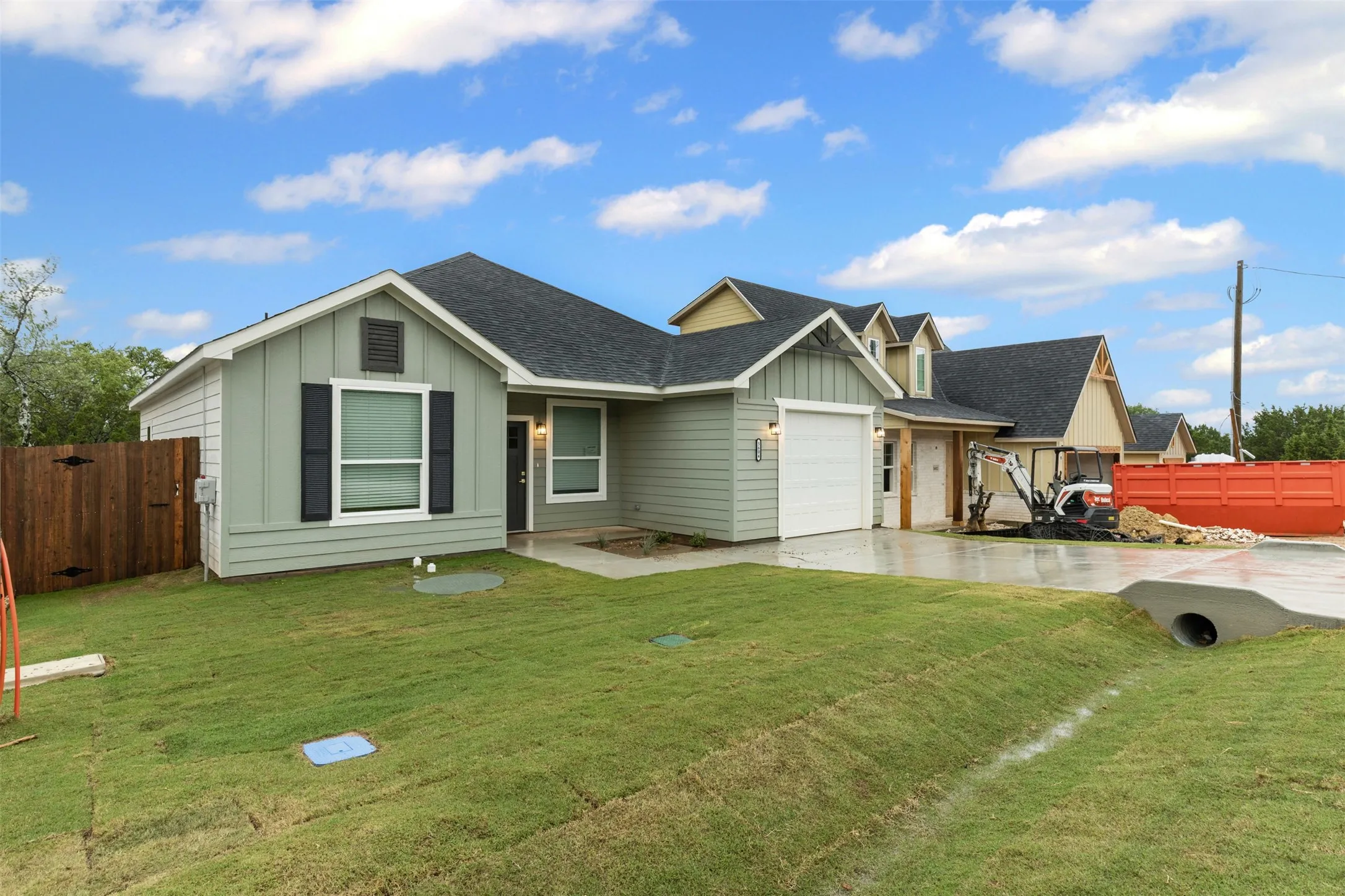 View of front facade featuring board and batten siding, driveway, a garage, and roof with shingles