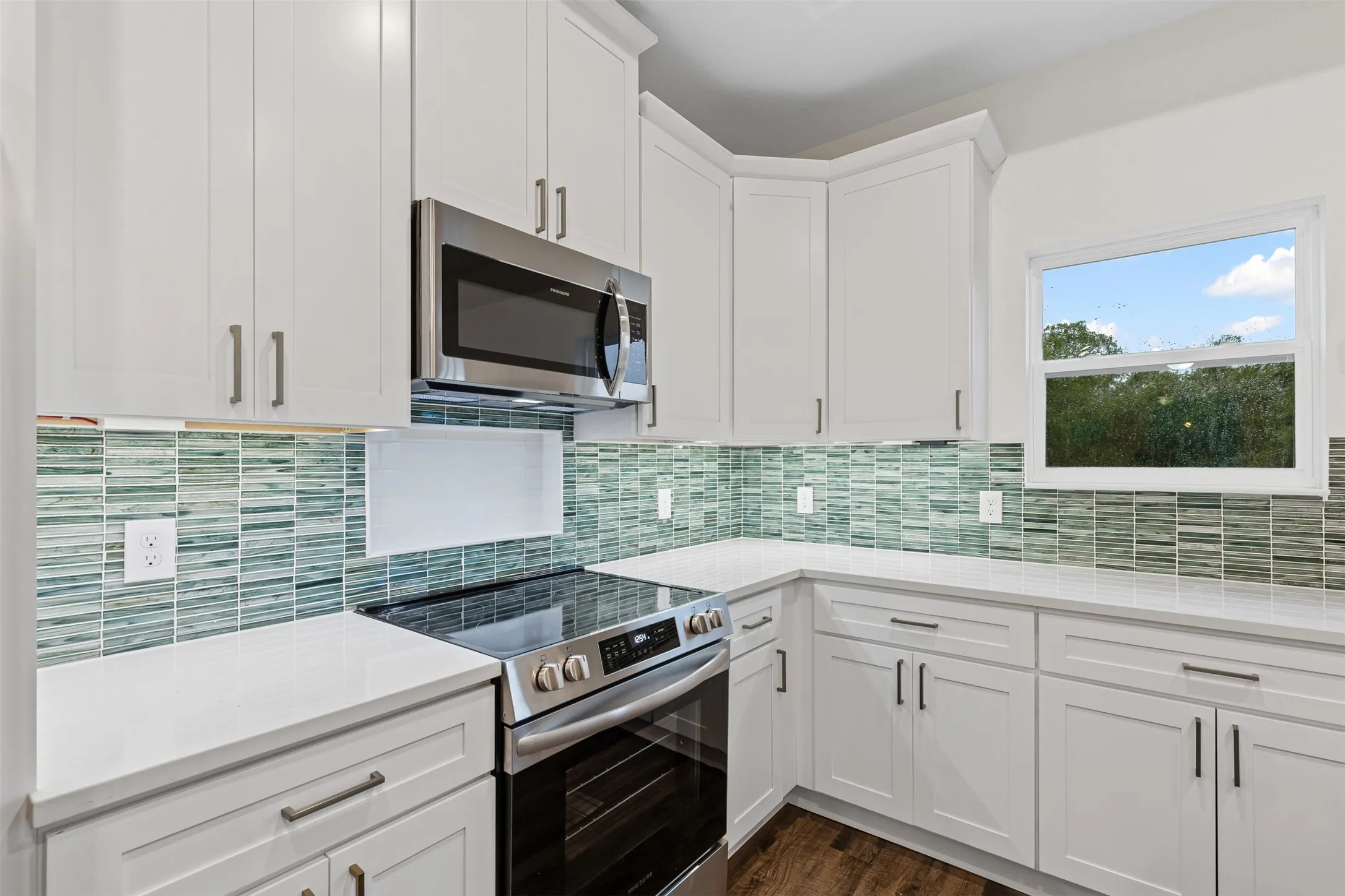 Kitchen featuring appliances with stainless steel finishes, white cabinetry, backsplash, and dark wood-style floors