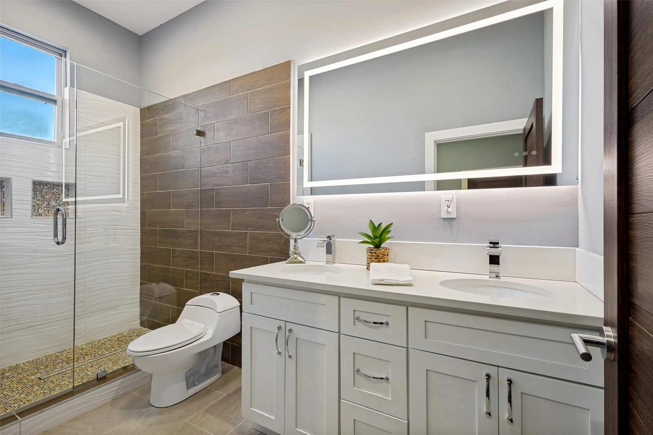 Large master bathroom with double sinks, Corian countertops, lighted mirror and custom oversized shower.