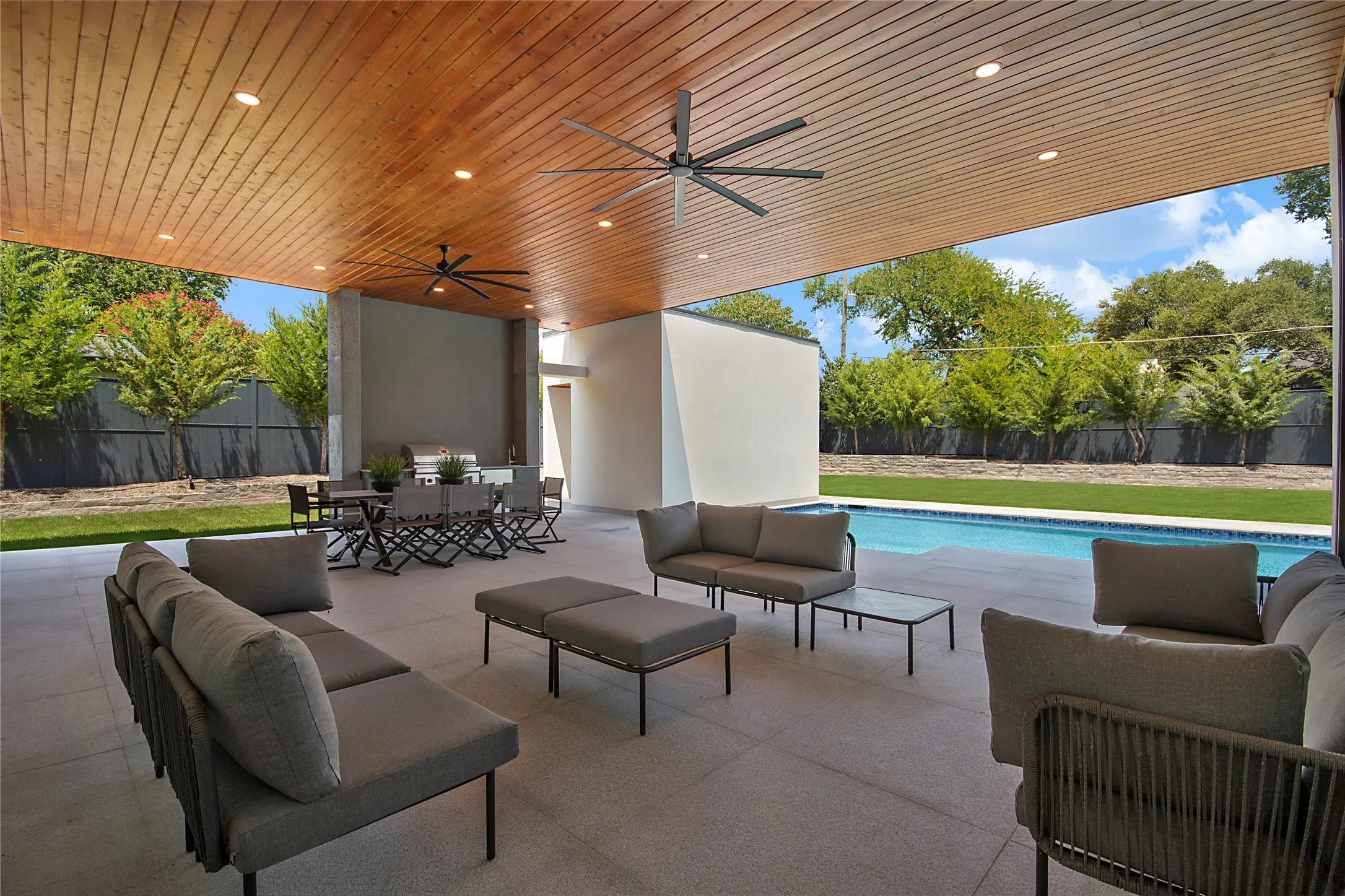 Expansive covered patio with wood-finish ceiling, recessed lighting, and ceiling fans