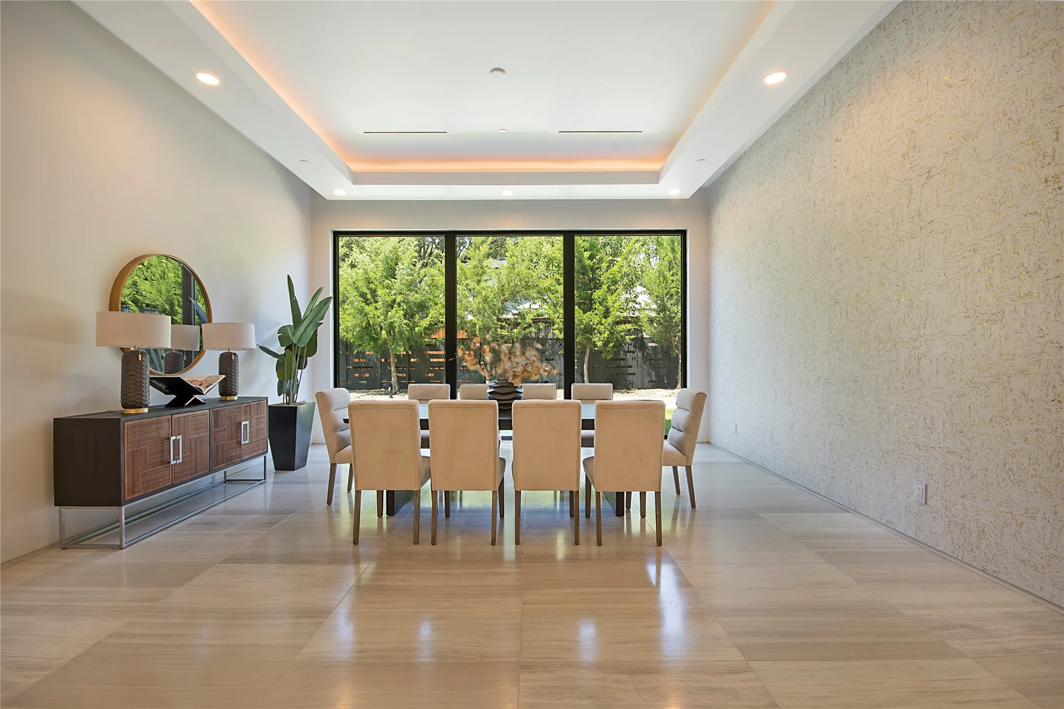 Recessed ceiling lighting, tray ceiling detail, full-height windows, textured accent wall, and large format floor tiling
