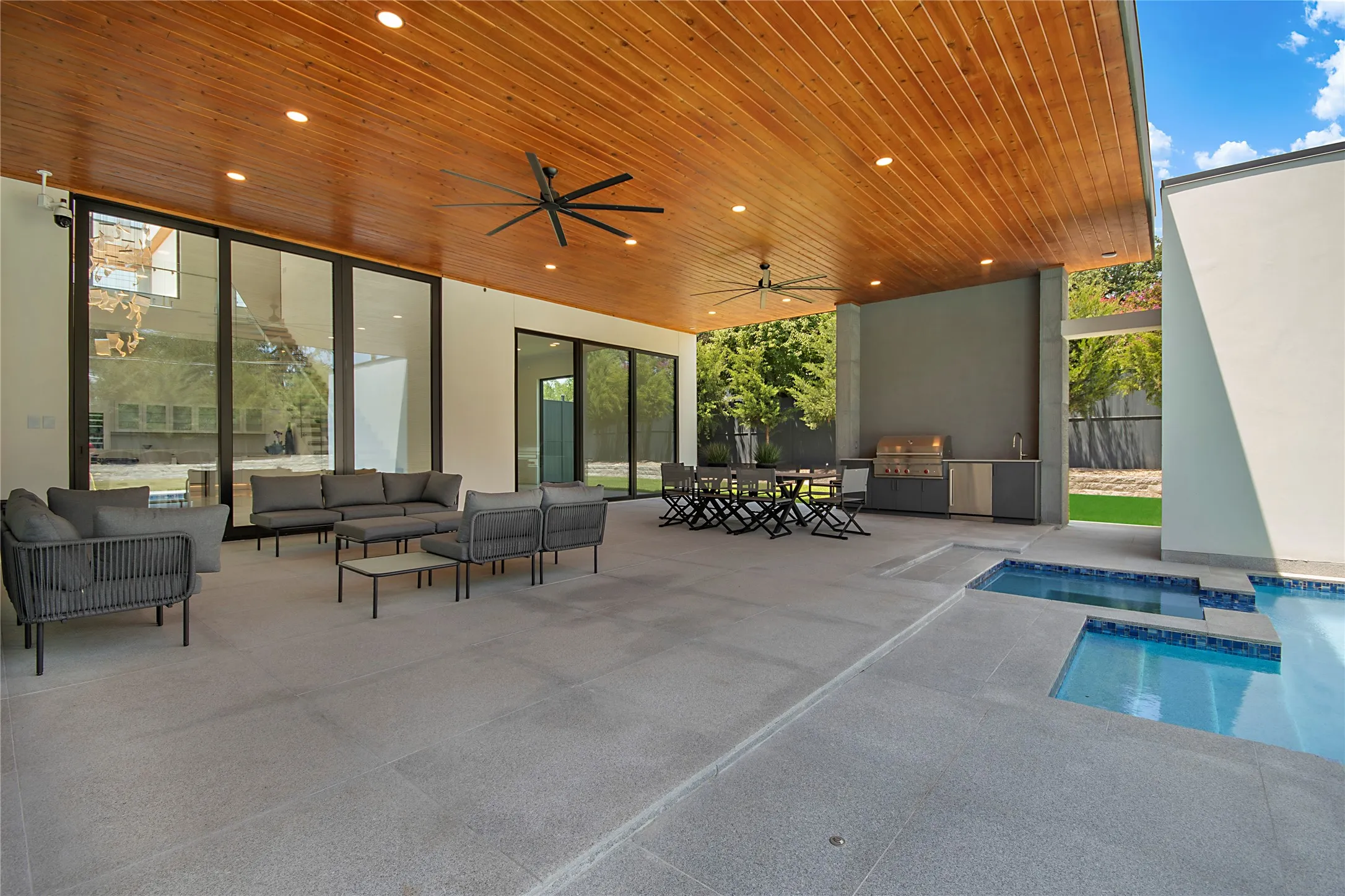 Expansive covered patio featuring a wood-panel ceiling, recessed lighting, and multiple ceiling fans