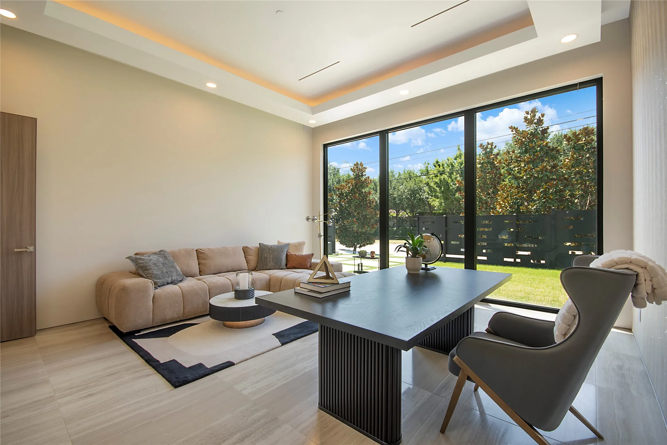 Expansive floor-to-ceiling windows, tray ceiling with recessed lighting, light-toned tile flooring, and a solid wood interior door