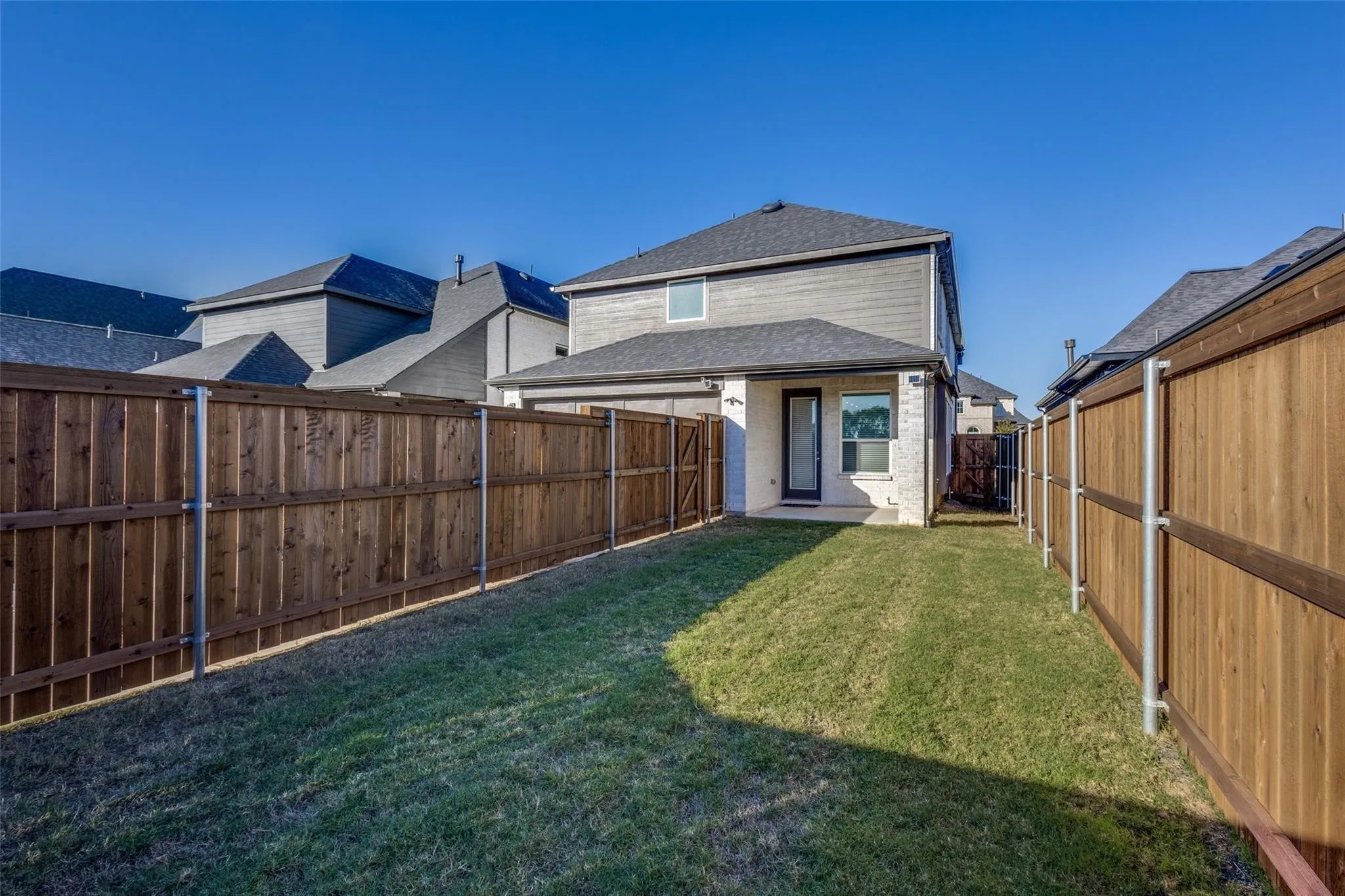 Manicured lawn with wood privacy fencing, stone and siding exterior, and a rear patio