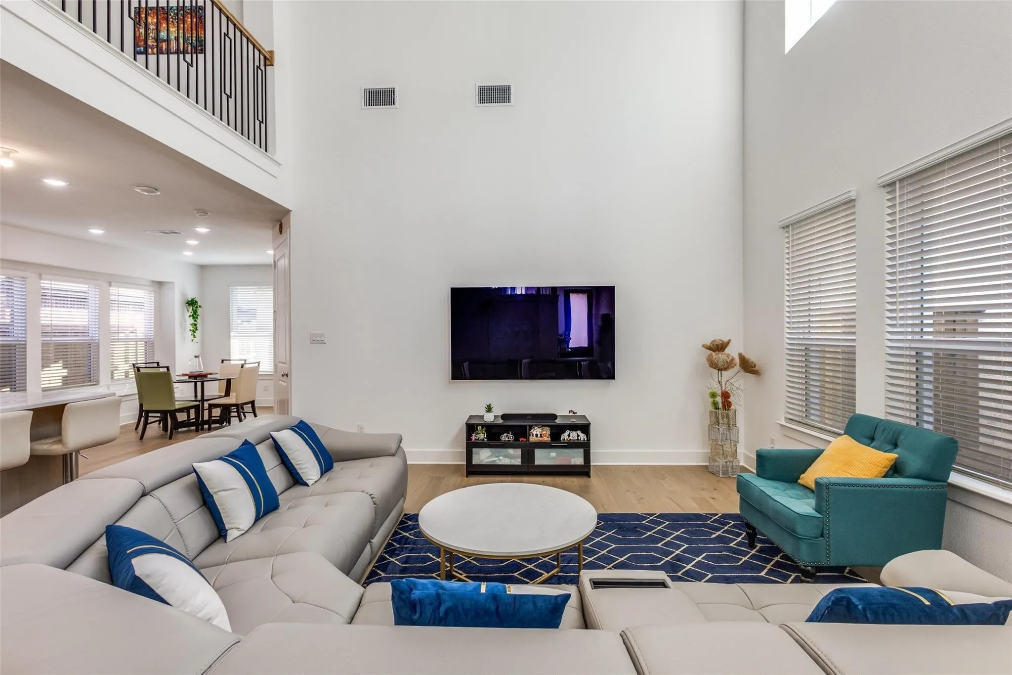 Double-height living space featuring wood-finish flooring, recessed lighting, and expansive windows