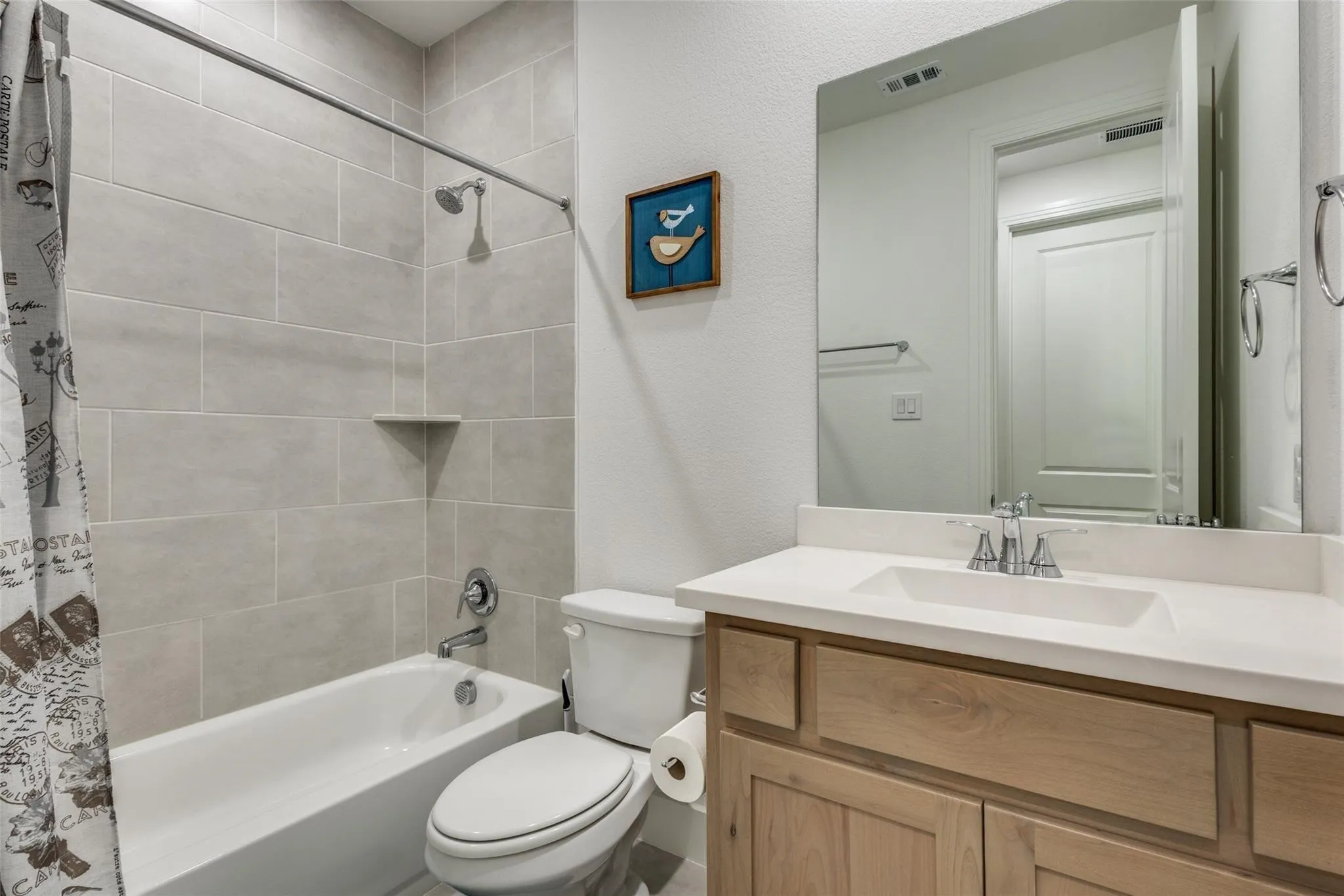 Bathroom featuring a single vanity with wood-finish cabinetry, a light-toned countertop, and an integrated sink